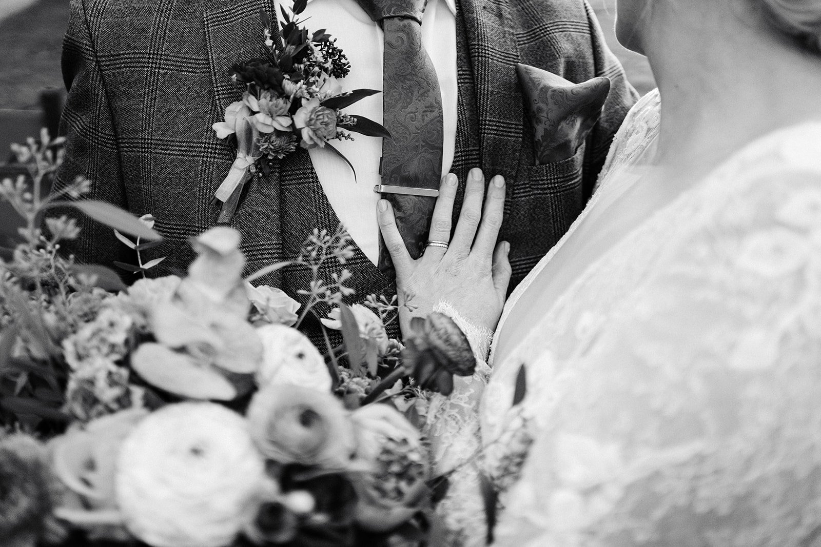 black and white close up image of bride and groom, image shows her ring, her suit and her lace sleeve. the normans York wedding