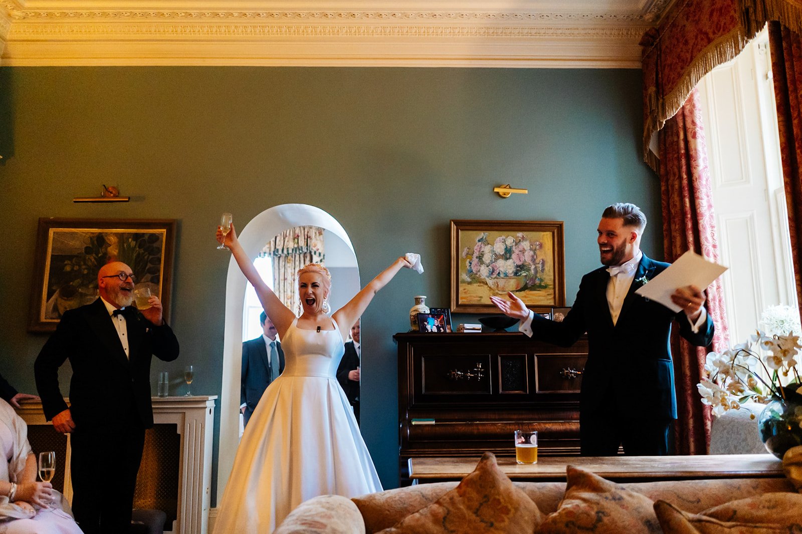 a bride and groom both cheer during speeches in a music room. wedding at toftcombs in Scotland