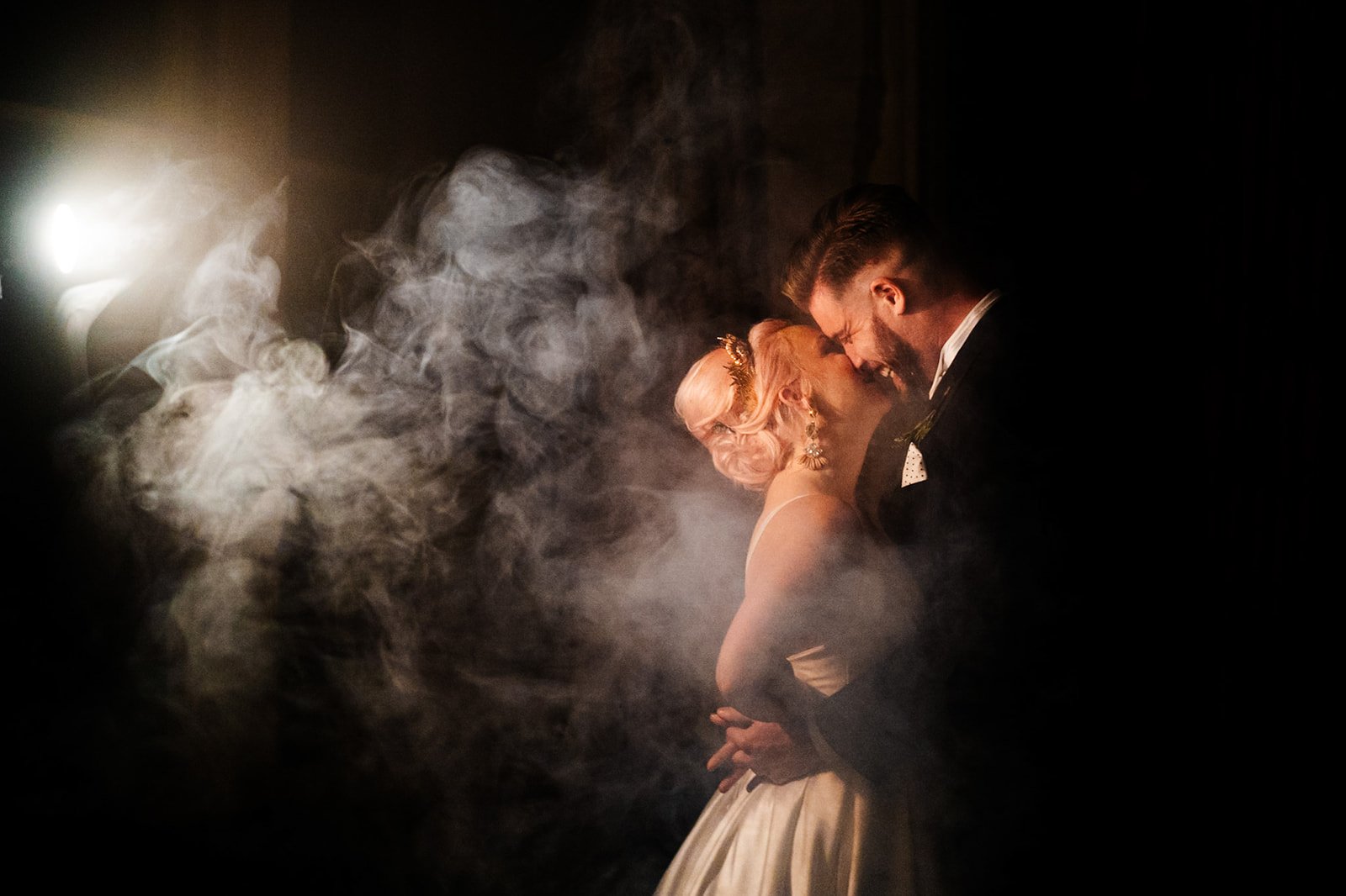 bride and groom in an embrace lit by a spotlight with smoke from the left. wedding at toftcombs in Scotland