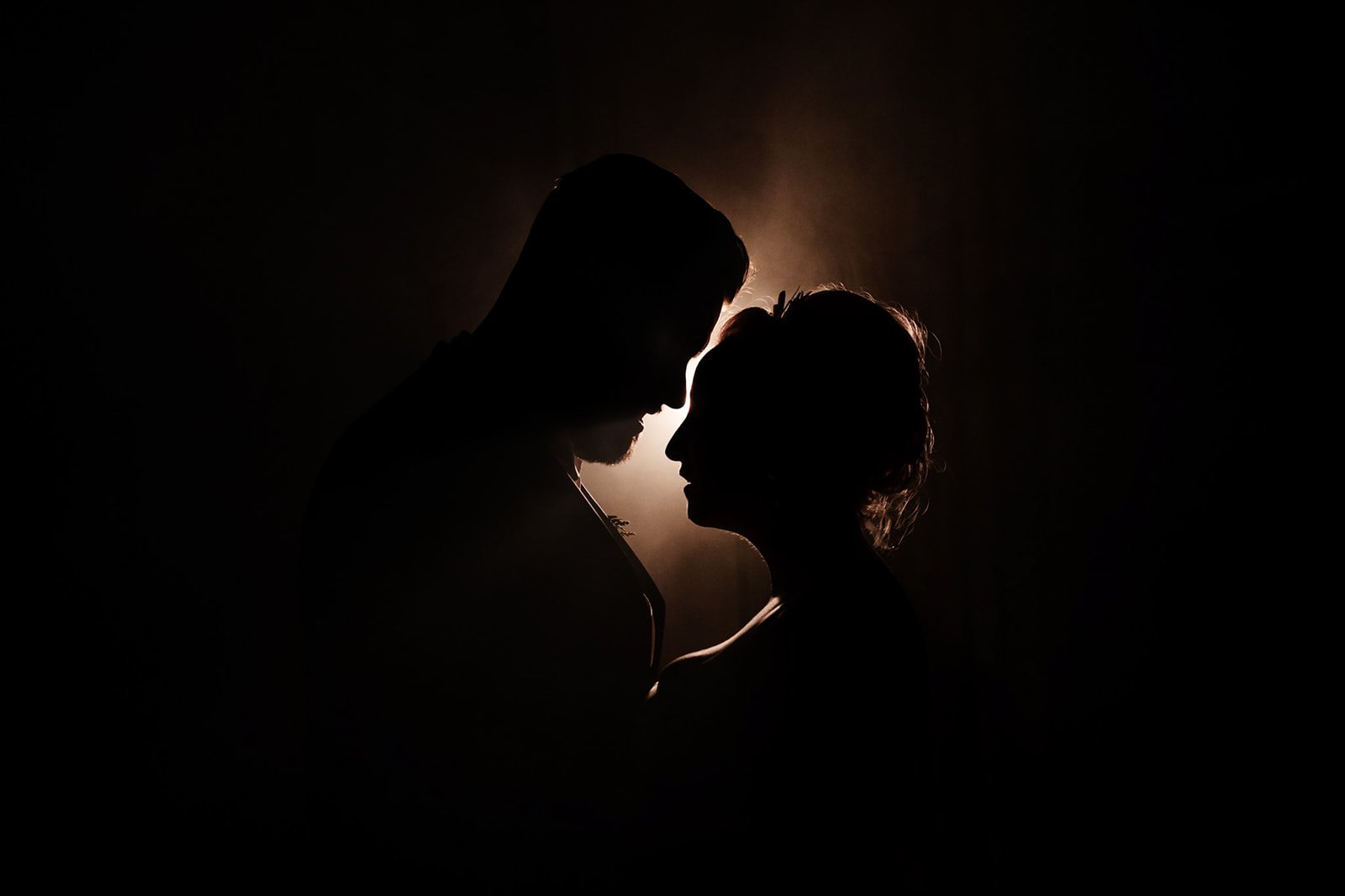 backlit and smoky silhouette portrait of the bride and groom in profile view. a smokey atmospheric shot of the bride and groom cheering and dancing. wedding at toftcombs in Scotland
