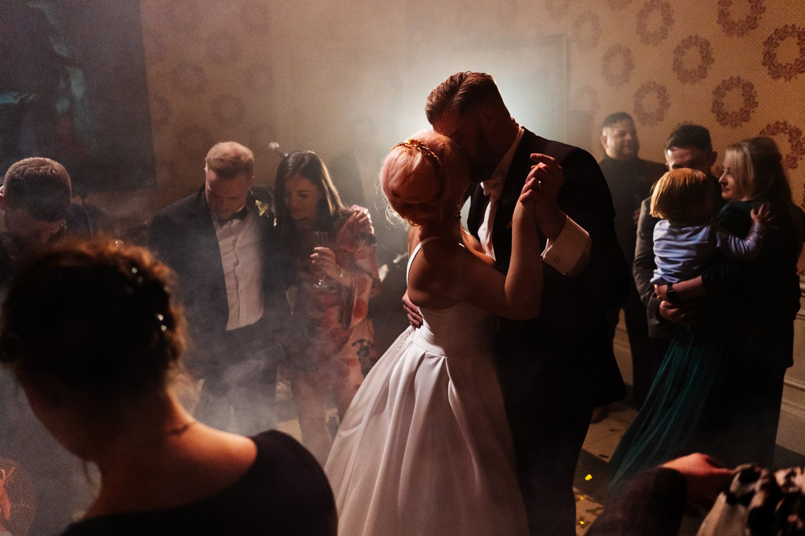 a golden light and smoky shutoff the bride and groom kissing while dancing. a smokey atmospheric shot of the bride and groom cheering and dancing. wedding at toftcombs in Scotland