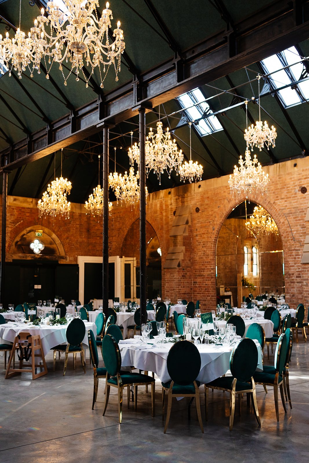 a portrait shot of an industrial room set up for a wedding meal with gold and green details. wedding at dalton old pump house 