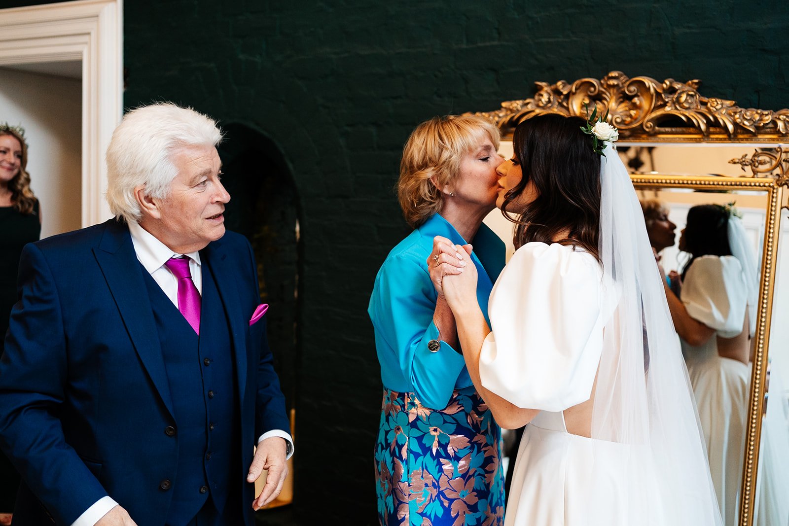 the bride and her mum kiss cheeks while her dad looks on. wedding at dalton old pump house 