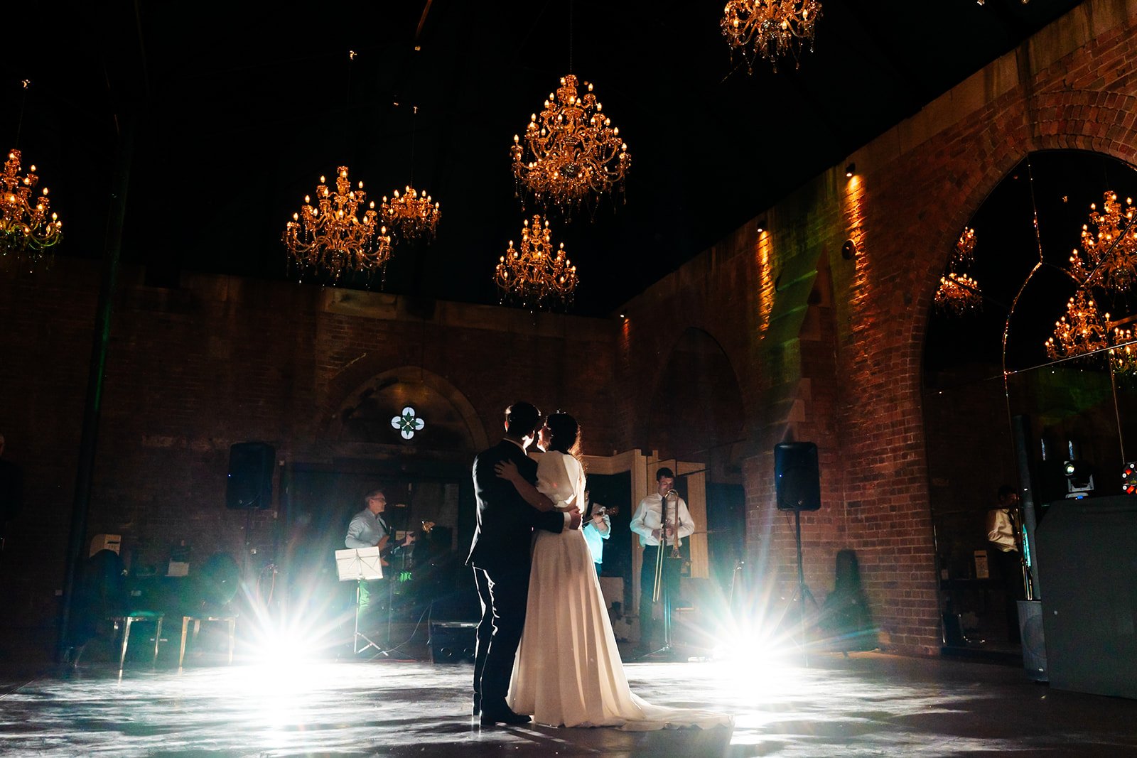 a dramatic shot of the bride and groom  dancing in an industrial room with chandeliers. wedding at dalton old pump house 