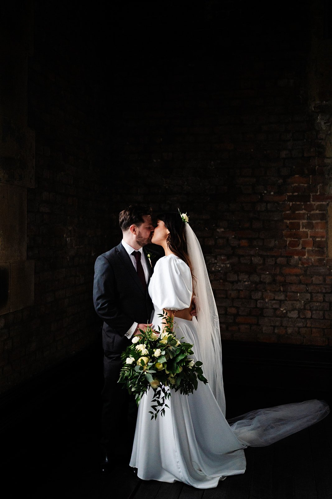 the bride and groom are lit from the side, a portrait shot and they kiss. wedding at dalton old pump house 