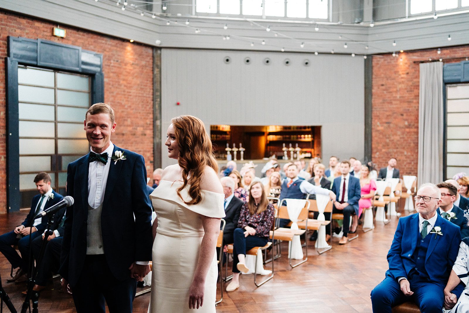 The bride and groom smile and hold hands during their wedding ceremony at Wylam Brewery in Newcastle