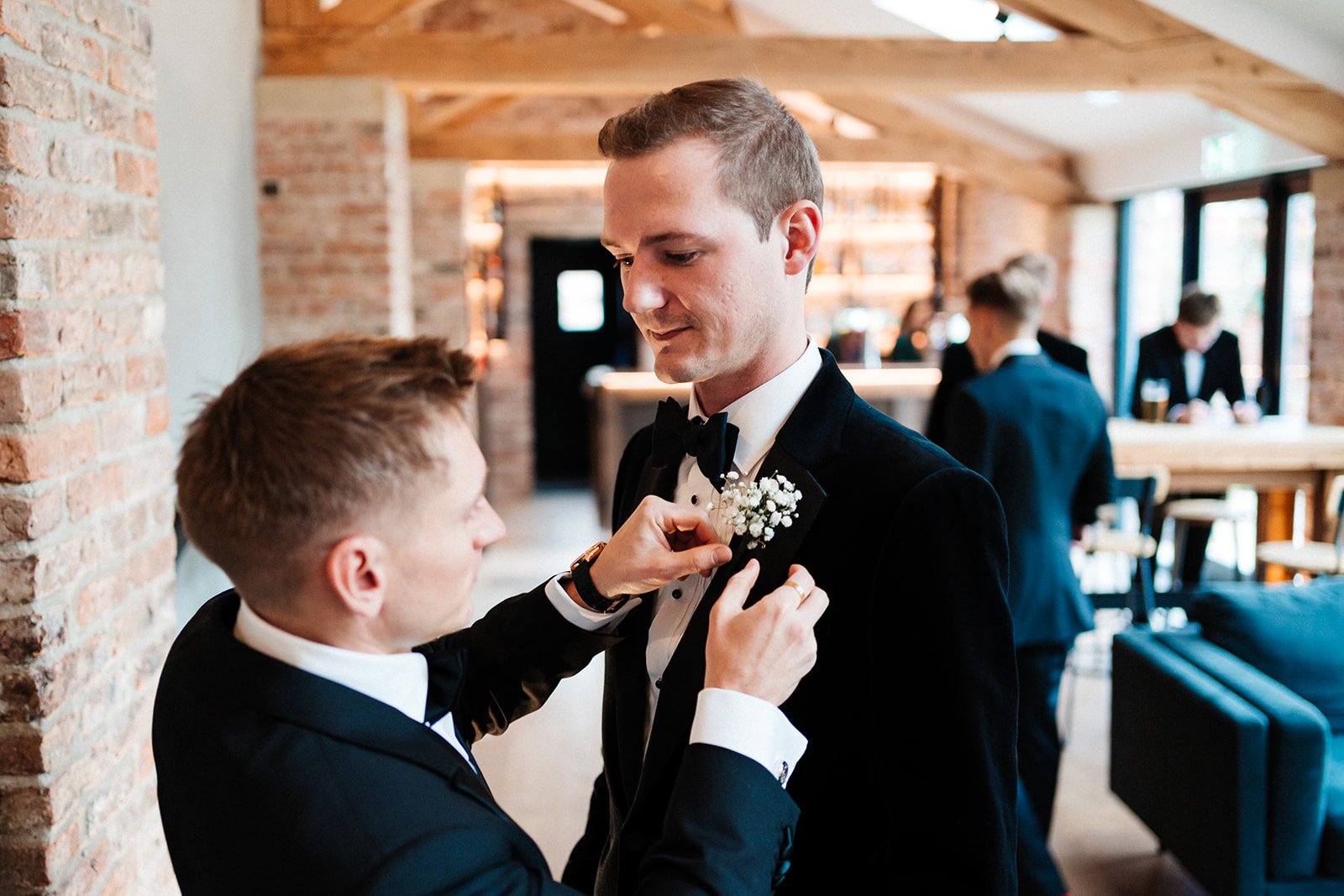 A groomsman does the grooms buttonhole ahead of the wedding ceremony at Thirsk Lodge Barns