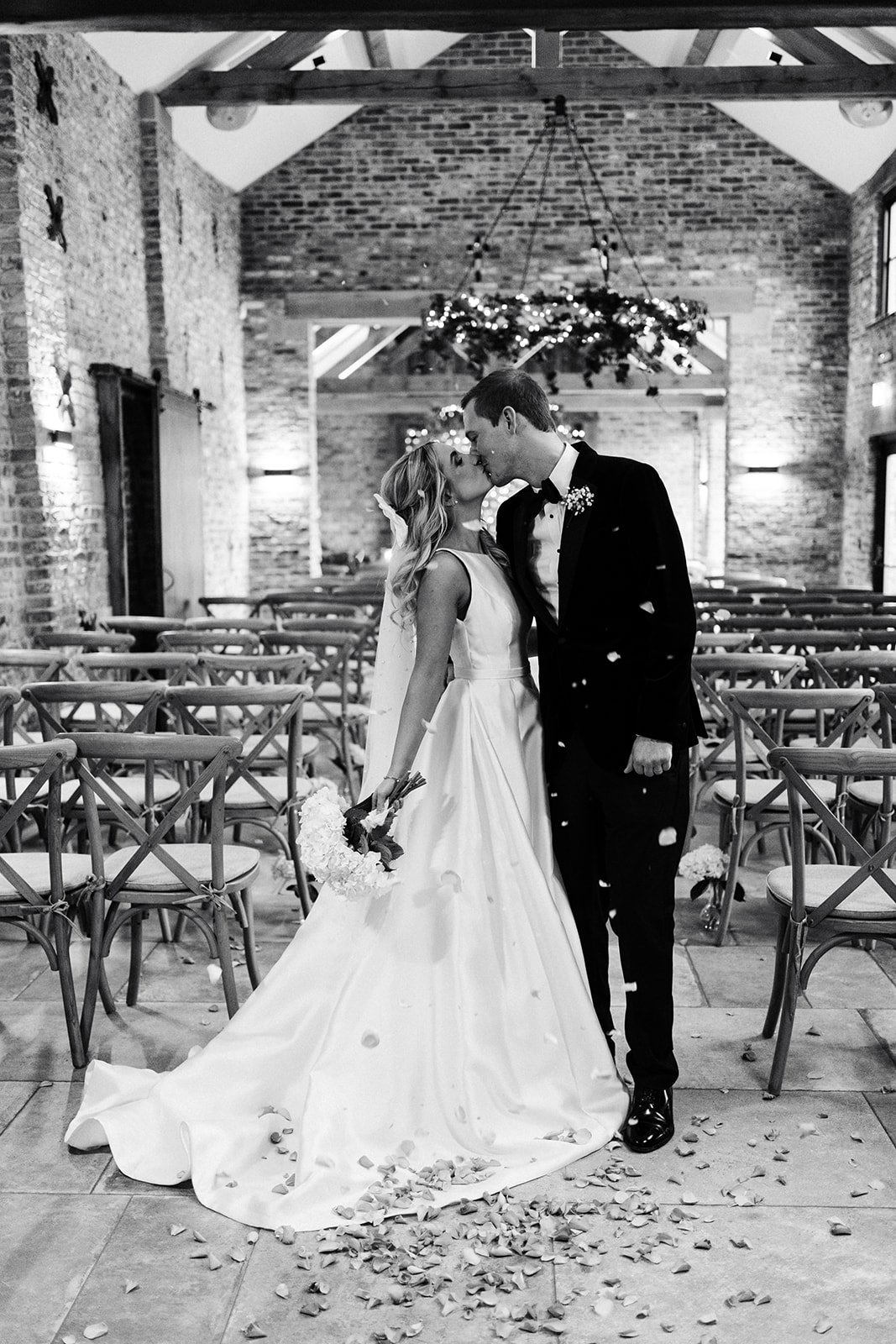 Black and white shot of a bride and groom kissing in an empty ceremony room at Thirsk Lodge Barns