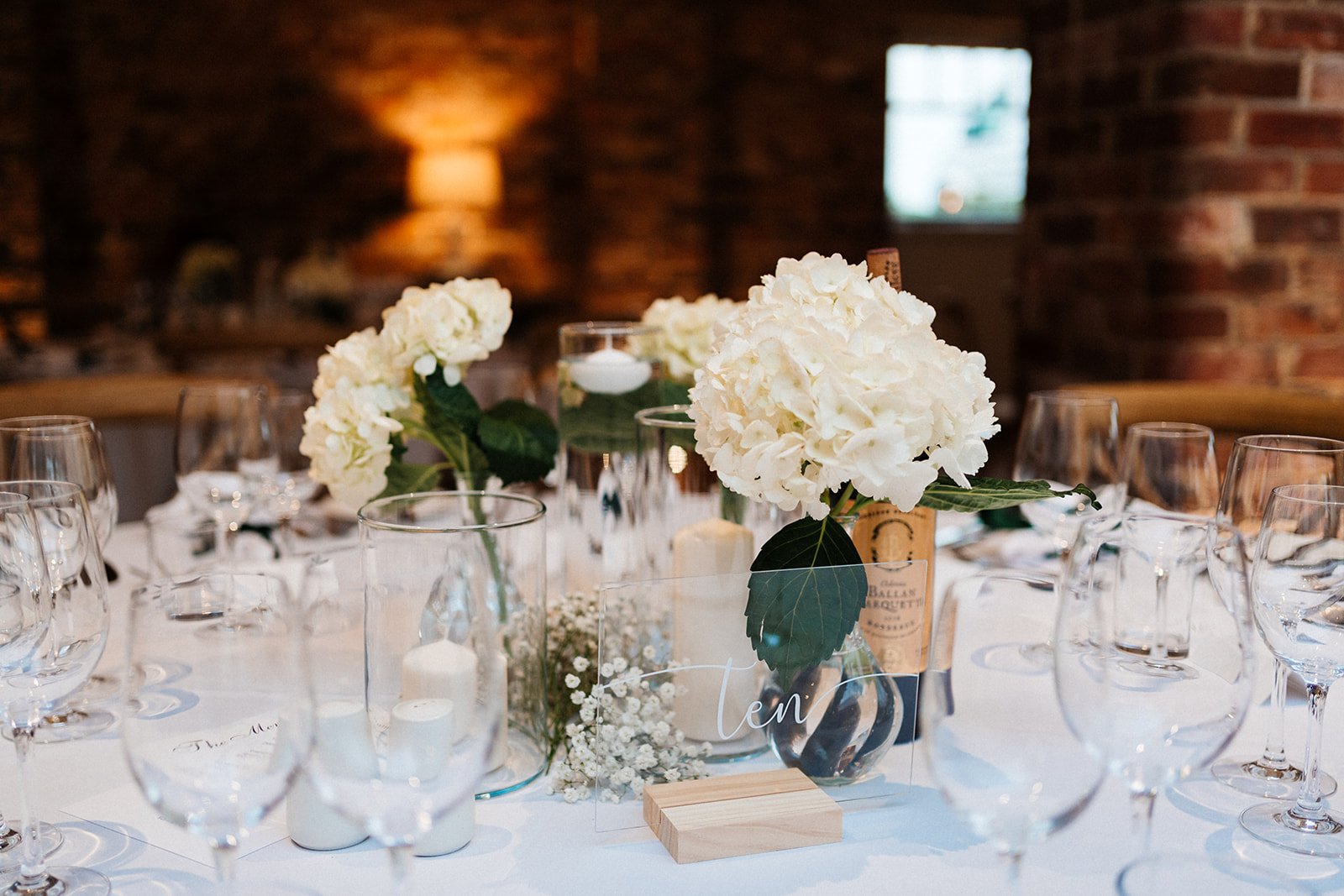 Wedding table centrepiece comprised of hydrangea flowers and a glass table name