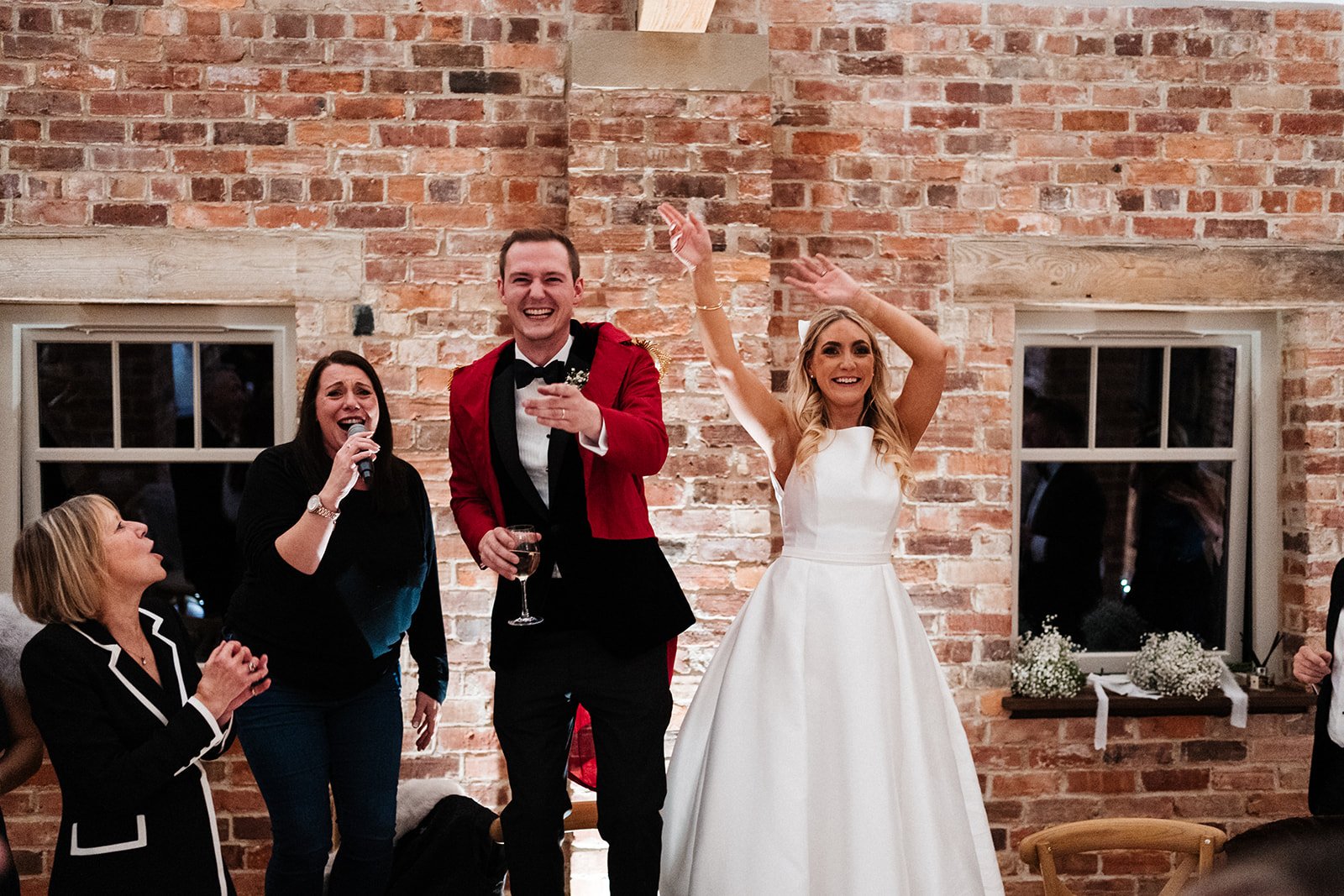 The bride and groom cheer while standing on chairs during their wedding reception mail at Thirsk Lodge Barns
