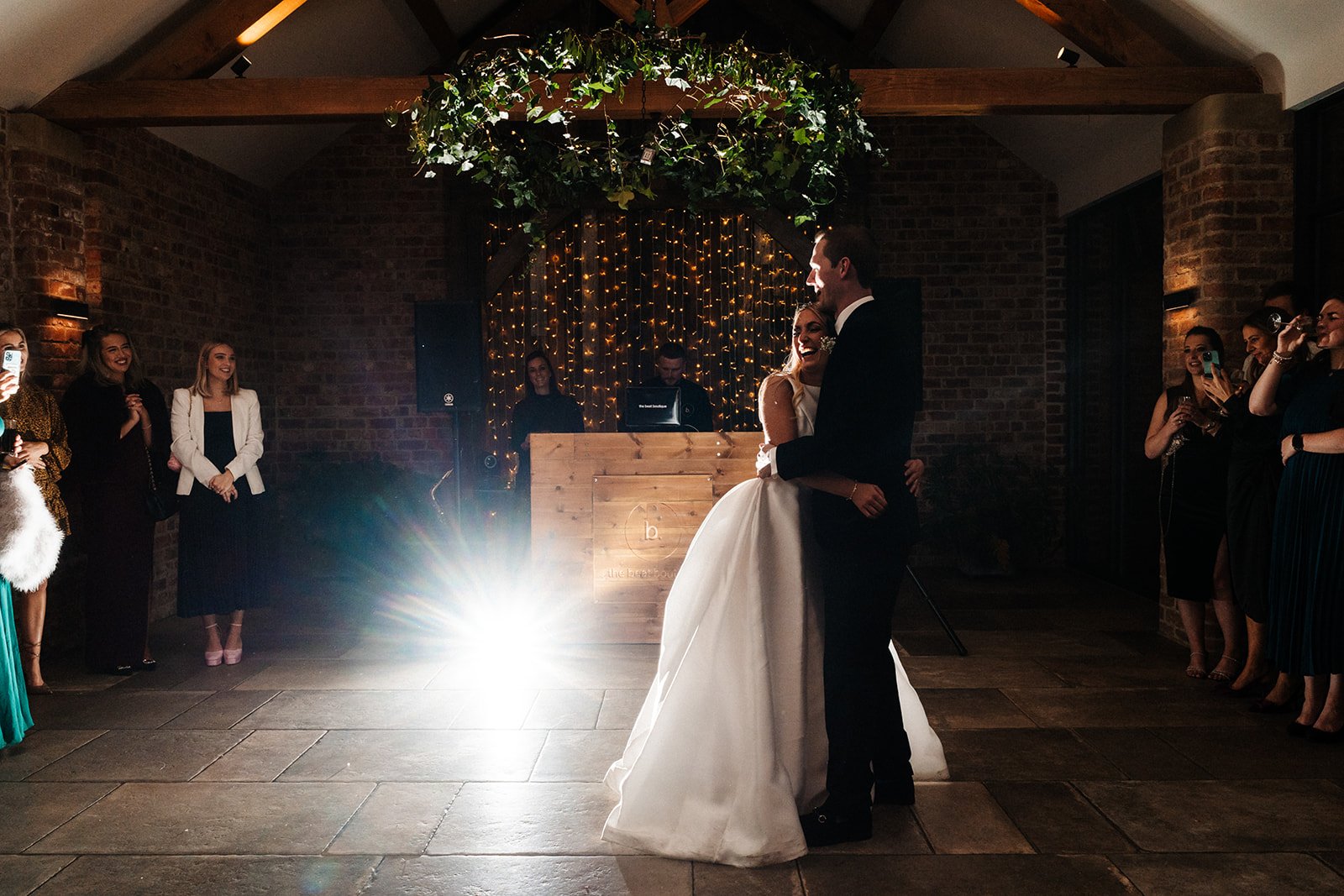 Bride and groom have their first dance in a barn ceremony room with a DJ behind them