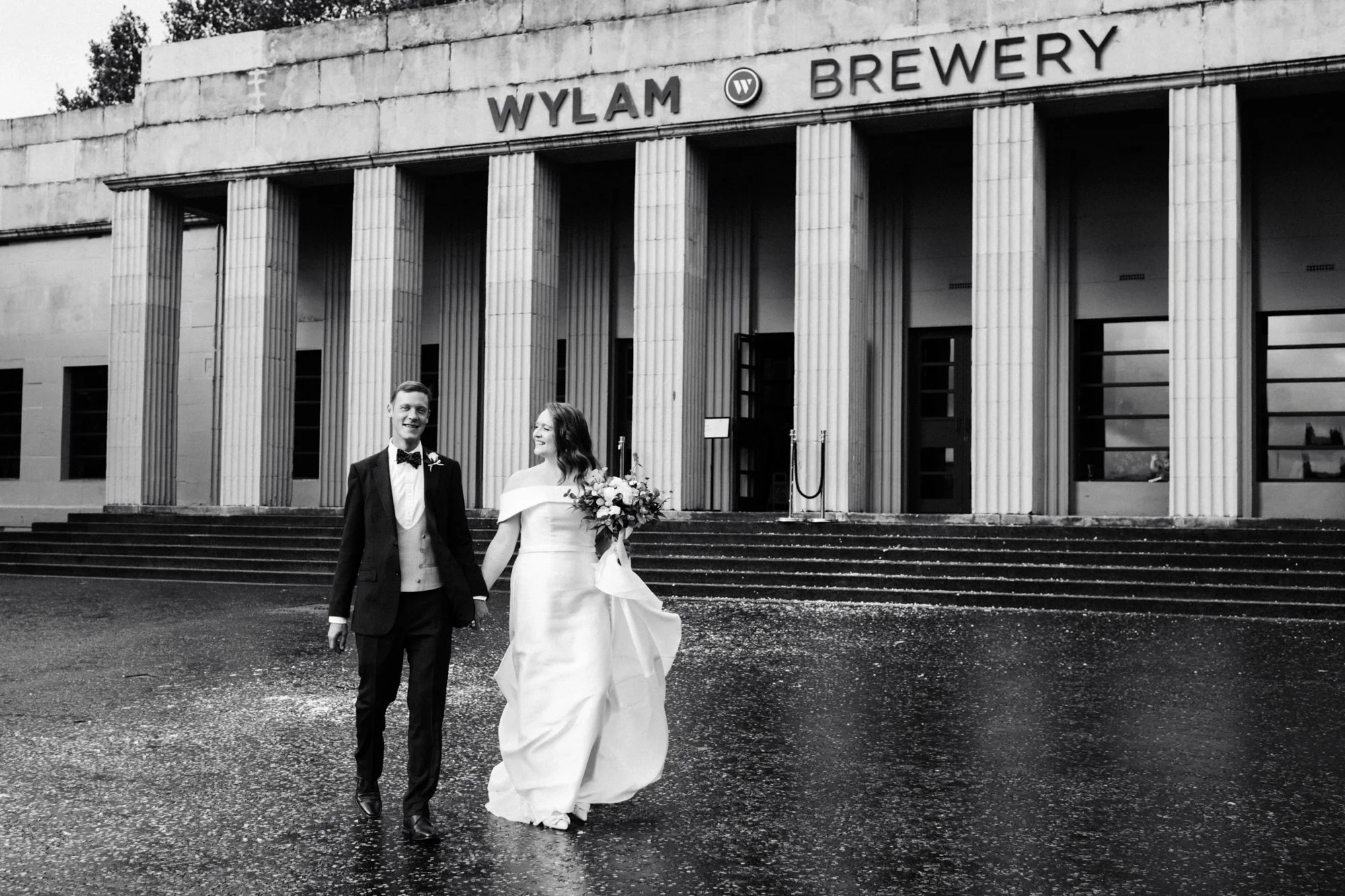 A black and white shot of a bride and groom walking outside Wylam Brewery in Newcastle. Northeast wedding photography