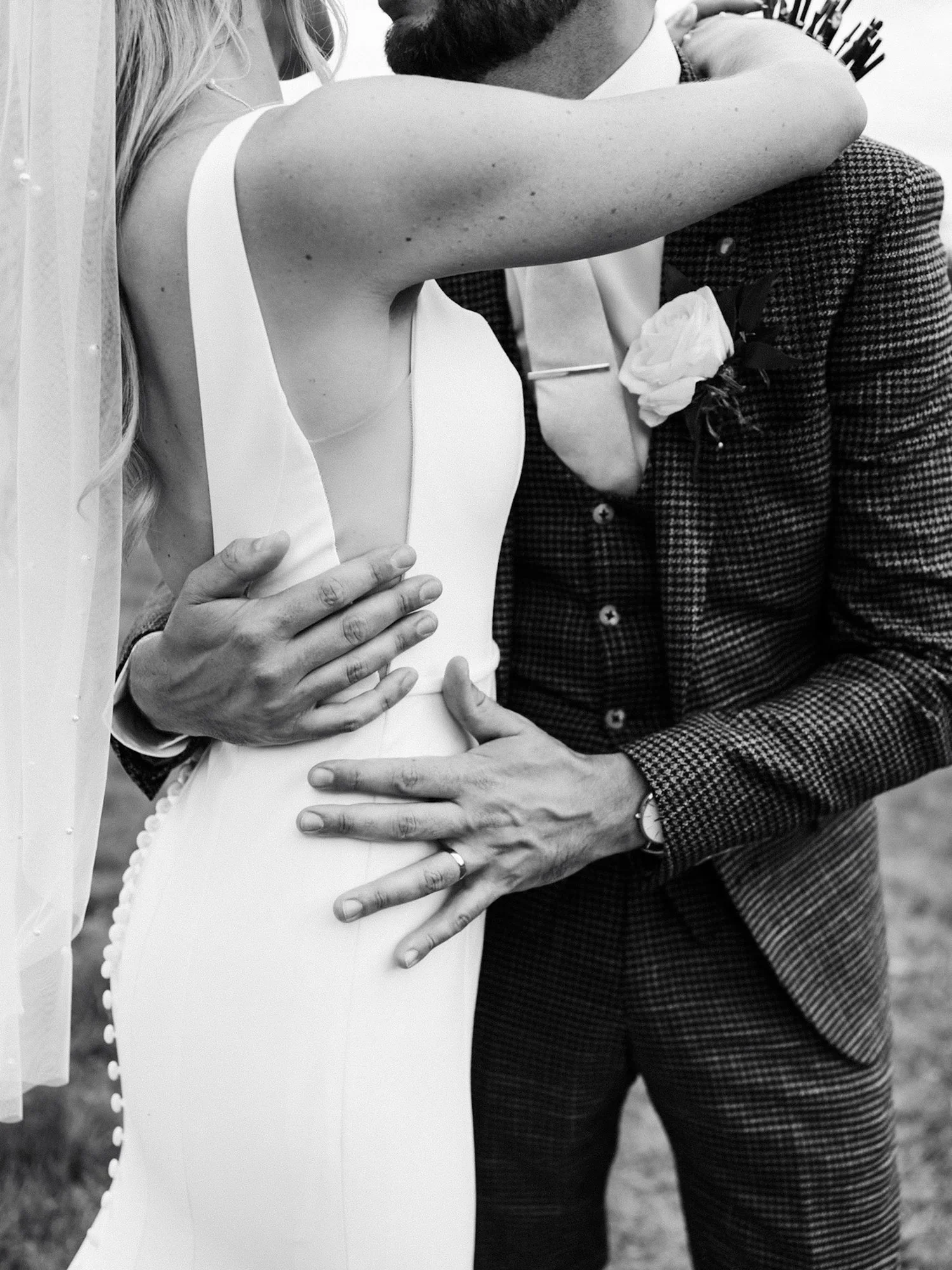 Close-up of a bride and groom holding hands and embracing each other at a wedding, in black and white. This was a Howard Court wedding near Great Ayton.