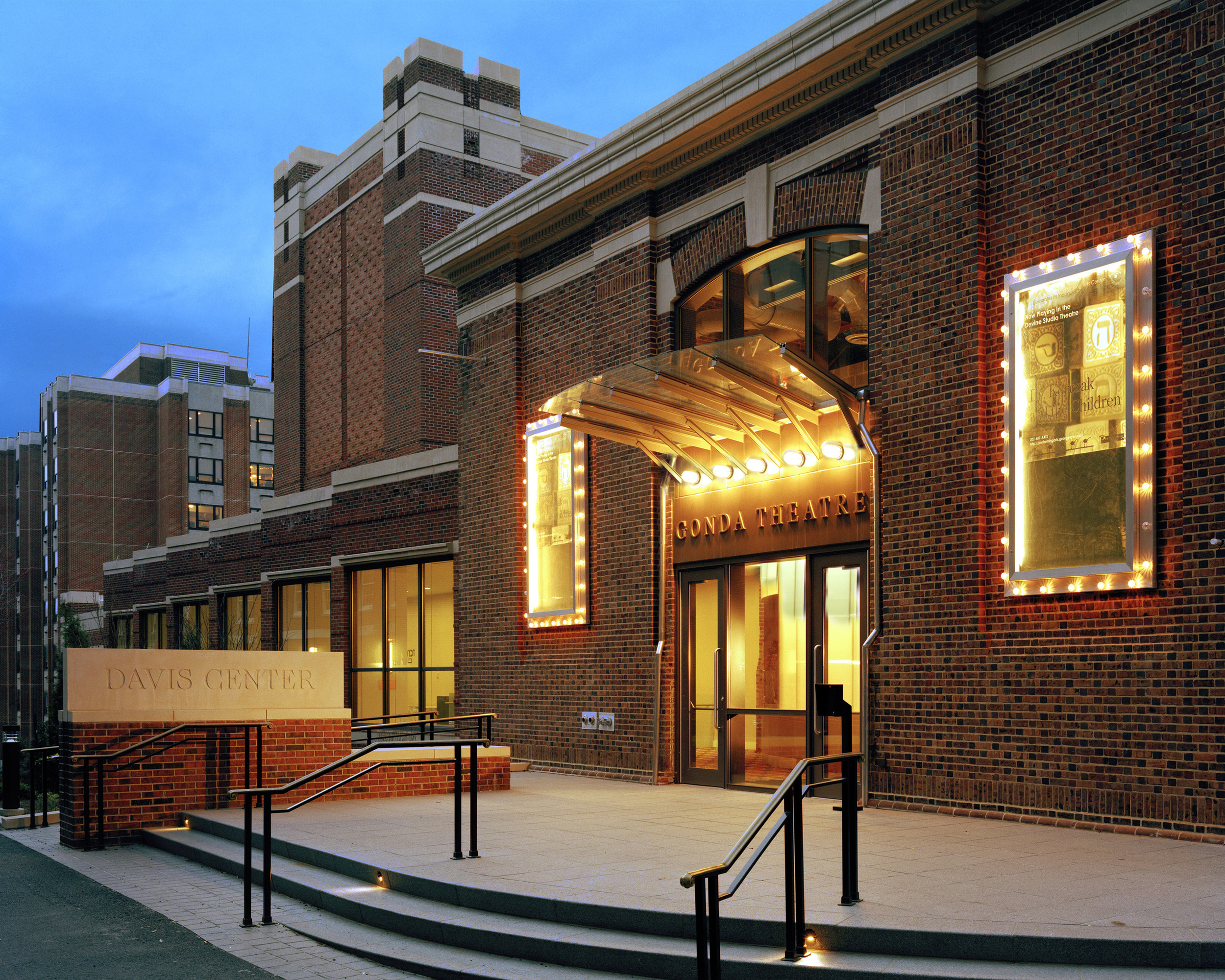 PROJECT: Georgetown University, Royden B. Davis Performing Arts Center LOCATION: Washington DC CLIENT: Georgetown University COMPLETION: 2005 SIZE: 56,000 Square Feet COST: $15 Million The Royden B. Davis, S.J., Performing Arts Center is the first building devoted to the performing arts at Georgetown. The Performing Arts Center combines two buildings; the 16,000 square foot existing Beaux-Arts Ryan Building and a new 40,000 square foot addition. The Center commands a hillside site overlooking a Jesuit cemetery. Named after Father Royden B. Davis, S.J., a past dean of the College, the Davis Center contains two halls: the 250-seat Gonda Theater and the 100-seat Devine Studio Theater, as well as scene and costume shops, rehearsal rooms, and offices. The intimate Gonda Theatre is the building’s heart, finished in warm wood tones with dark blue and red side walls and vibrant patterned seating fabric. The Gonda Theater’s proscenium is the first on campus, permitting of a range of dramatic productions and providing a flexible environment for scenic design. The scene and costume shops and rehearsal rooms function as non-traditional classrooms, sized to allow faculty and students to gather, collaborate, and experiment. The existing Ryan building, built originally as a gymnasium, is now the Center’s main lobby and the theater entrance. This interweaving of new and old construction permitted the smallest possible footprint on the site, simplifying the theater’s placement between buildings and along roadways. A saw-tooth corridor connects the lobby to the Devine Studio theatre, a fully flexible black-box theater, one level below. The translucent oval that announces the theater’s presence inside the lobby is visible at night from the main campus entrance. Georgetown’s students of design and technical theater have flourished, able to learn in a facility that supplies well-outfitted shops, flexible performance spaces, and space for experimentation.