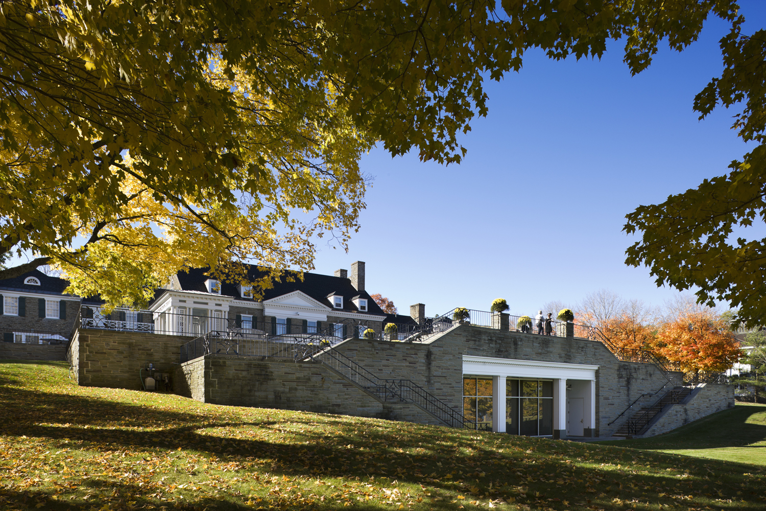 PROJECT: Fenimore Art Museum, American Indian Wing LOCATION: Cooperstown, New York CLIENT: New York State Historical Association COMPLETION: 1985 SIZE: 48,000 Square Feet COST: $5.3 Million The New York State Historical Association commissioned H3 to design a museum dedicated to the study of New York State and American history and culture, as well as an impressive collection of over 700 Native American artifacts donated by notable collectors Eugene and Clare Thaw. The mission was to create an aesthetically pleasing, functional space within the context of the natural setting on a grassy slope overlooking scenic Lake Otsego. Arriving at Fenimore House Museum, one enters through an imposing neo-Georgian portico into a small entry vestibule. A grand double stair descends to the central exhibition hall below. This stately room, supported by ten columns of solid Kasota stone, offers access to two galleries, the study center, and support facilities. Because of the sloping site, the hall also offers magnificent, unexpected views of the lake and surrounding hills. The 121-seat auditorium is a venue for educational programs, lectures, films and concerts for school groups, graduate students and the general public. The study center provides scholars, students, and the general public access to objects from the Thaw Collection not on display in the galleries. To protect the collection’s many fragile and light-sensitive objects, H3 created an environment that maintains stable temperature and humidity and provides a shield from harmful light and contamination. Precautionary measures include fiber optic lighting, ultraviolet filters for all light sources and construction materials with acceptable off-gassing characteristics.