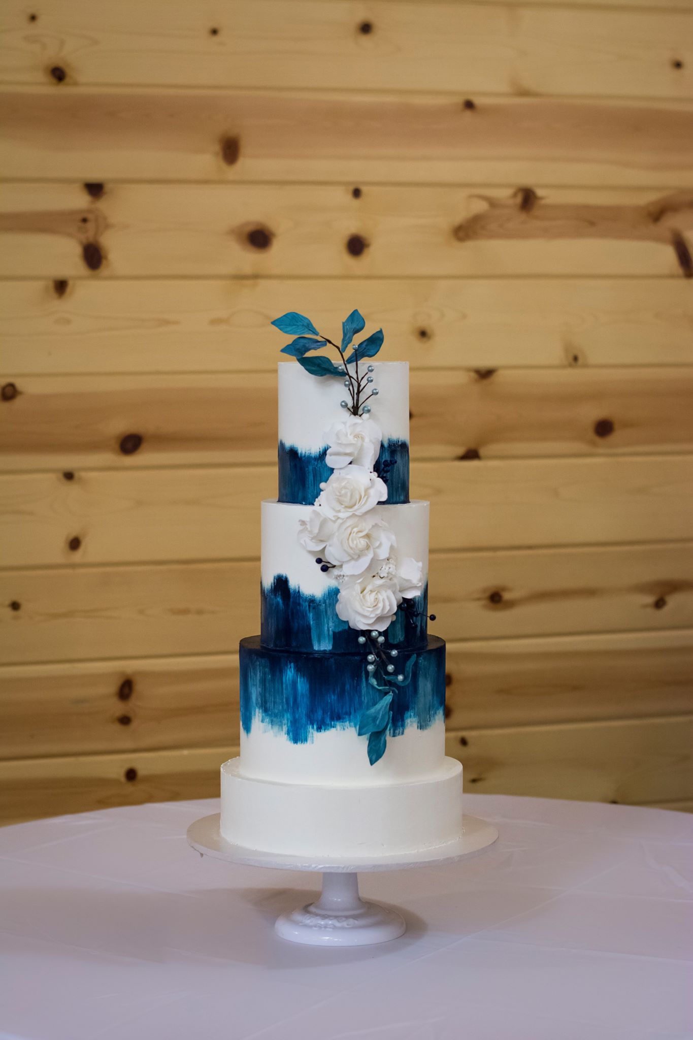 Jamie: Here you see a hand painted watercolor brushstrokes, sugar dough roses, berries, and wafer paper leaves, this cake is finished in our Swiss meringue buttercream.