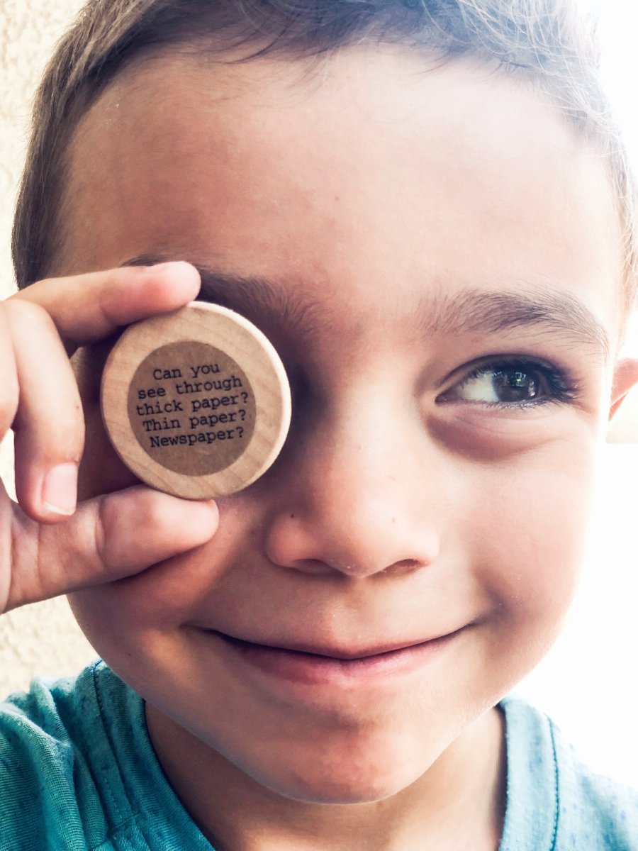 Little Boy Holding a Wooden Coin from an Idea Box Kids Against His Eye.jpg