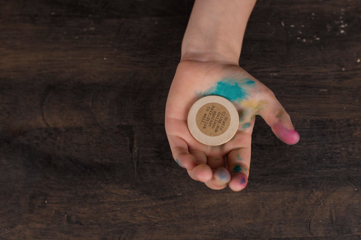 A Child Holding a Wooden Coin from Idea Box Kids.jpg