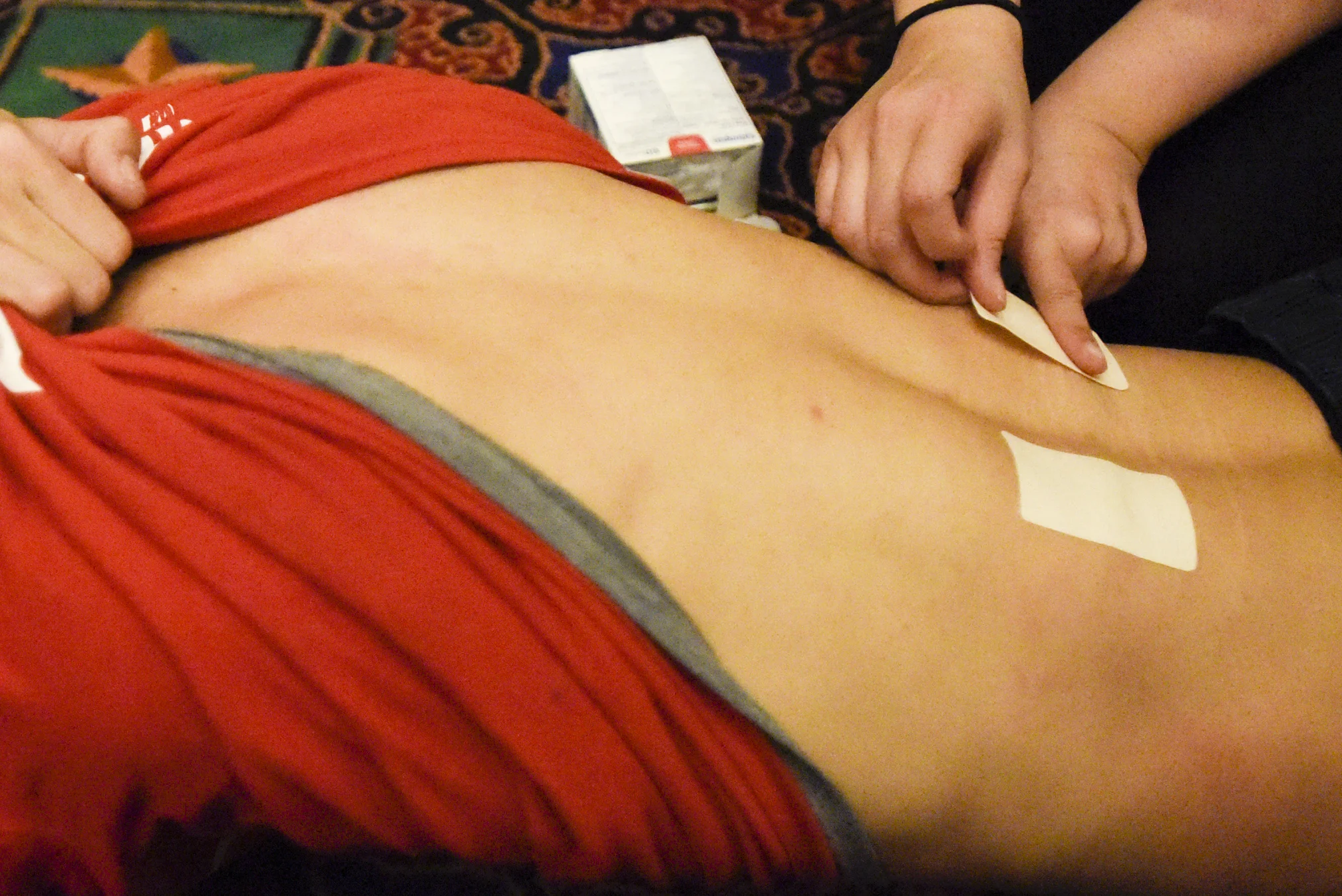  Phổ Hiền lion dancer Jessica Pham applies Salonpas Pain Relief pads onto Daniel Van's lowerback right after a major performance on Saturday, Feb. 17, 2018 at Ameristar Casino in Kansas City, Missouri. As part of the varsity stunt team, Van did a lar