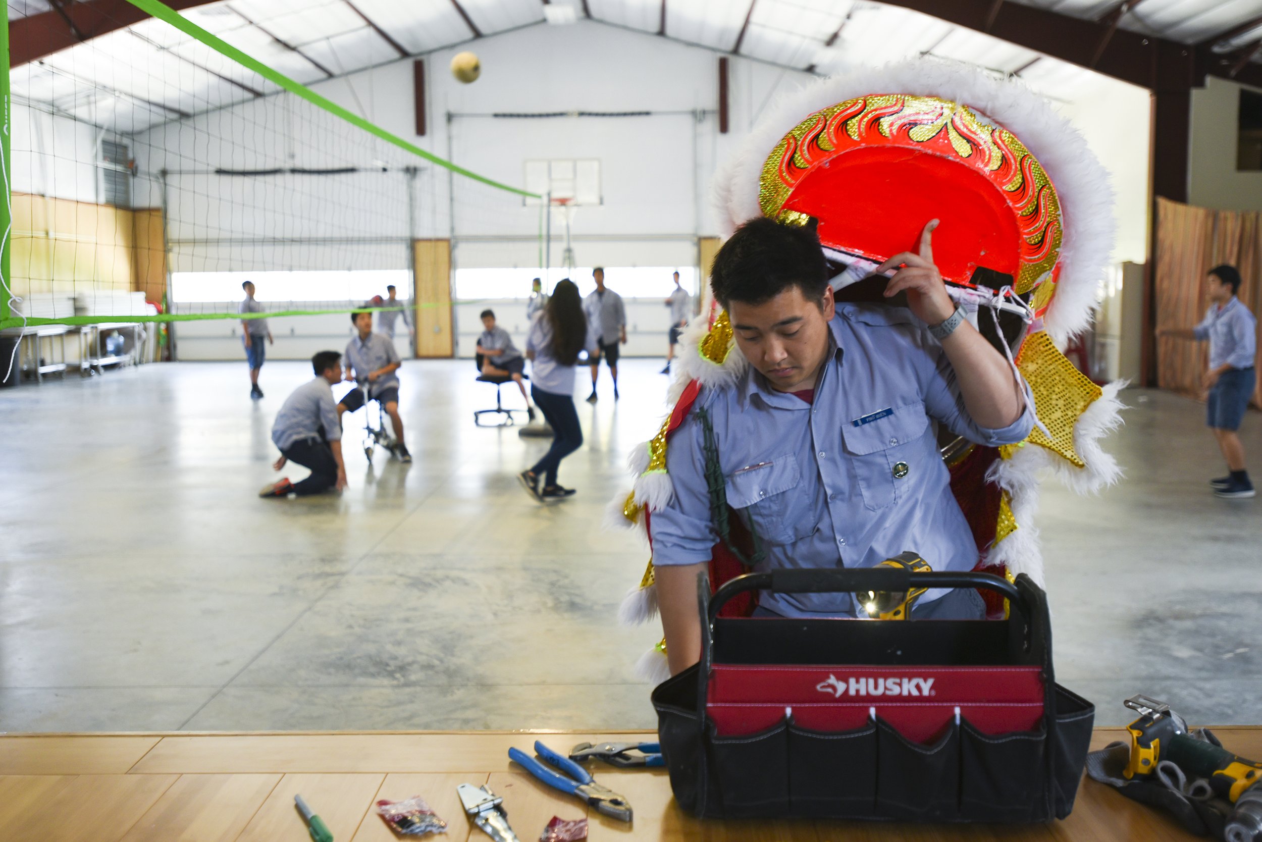 Huynh truong, or leader, Kieu Duong works on fixing a lion dance head while younger members play in the gym on April 29, 2018 at Pho Hien Buddhist Temple. Vietnamese class was cancelled for the older members, because their teacher was not present.
