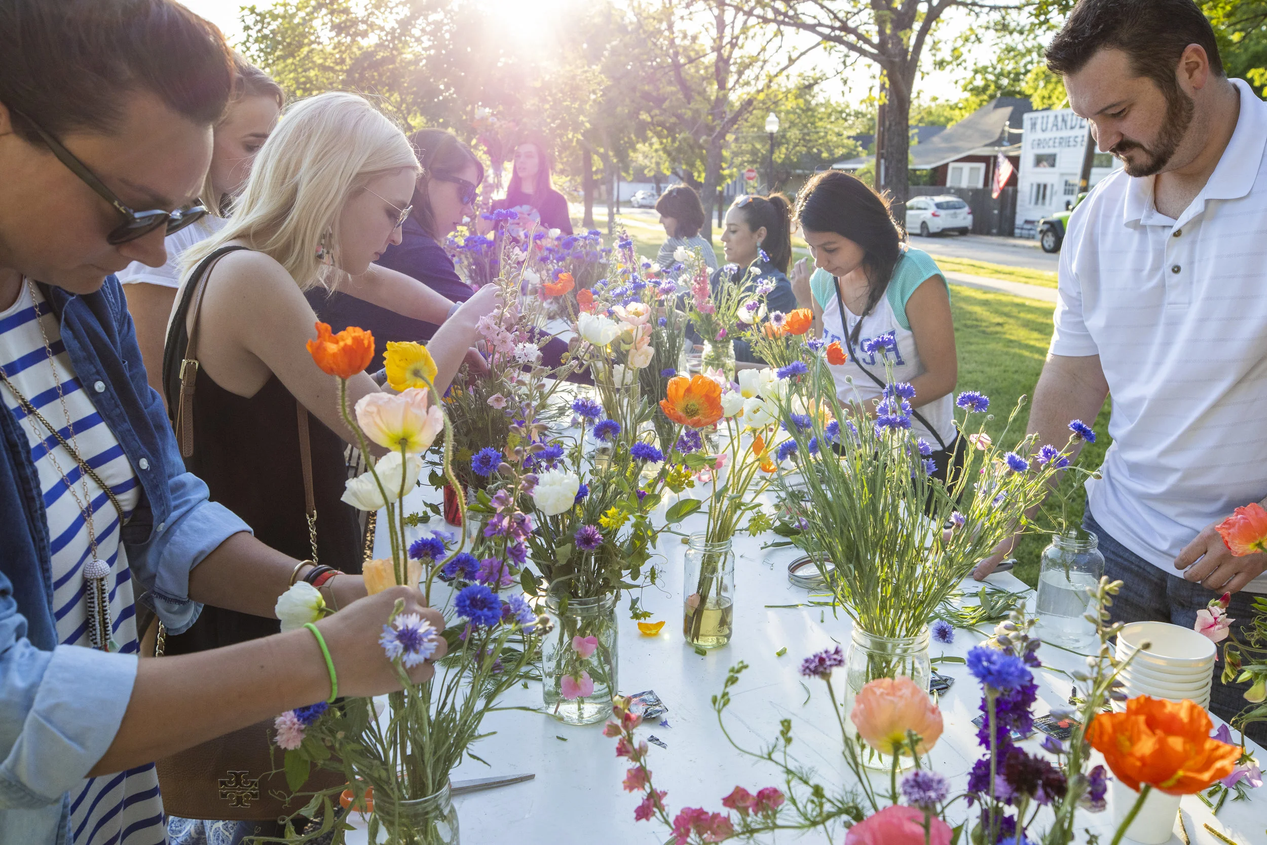  The long table in Fairmount Community Park is filled with flowers, Mason jars, water spills, and flower food while people are busy exploring their arranging skills.  Photo by Sam Bruton  