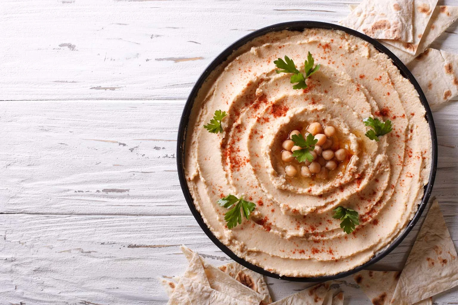  Classic hummus with parsley on the plate and pita bread. horizontal top view 