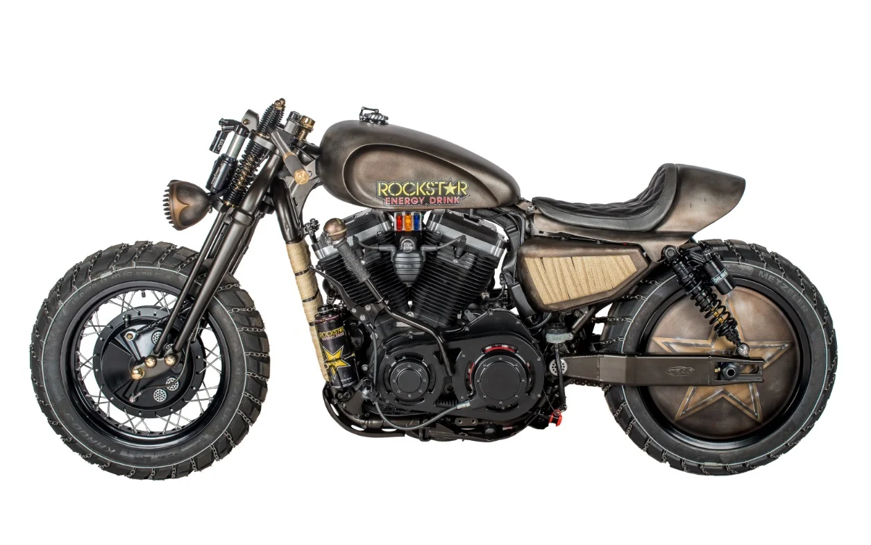 This motocross-inspired custom is the second project bike Shaw Speed has completed with the energy drinks brand Rockstar. Based on a 48 Sportster, it was commissioned by the Mad Max movie sponsor as a promotional tool to launch their Fury Road video game. It’s got Springer-style forks with a downhill mountain bike front shock. Swingarm is by Trac Dynamics with twin Ohlins. Disc is by Mooneyes. Tyres are 17in Metzeler Karoos. Motor is dressed with Figure Machine rocker covers, cam cover, front sprocket cover and air filter. Primary drive is open (rare for a Sportster) with Trac Dynamic USA Belt Drive.