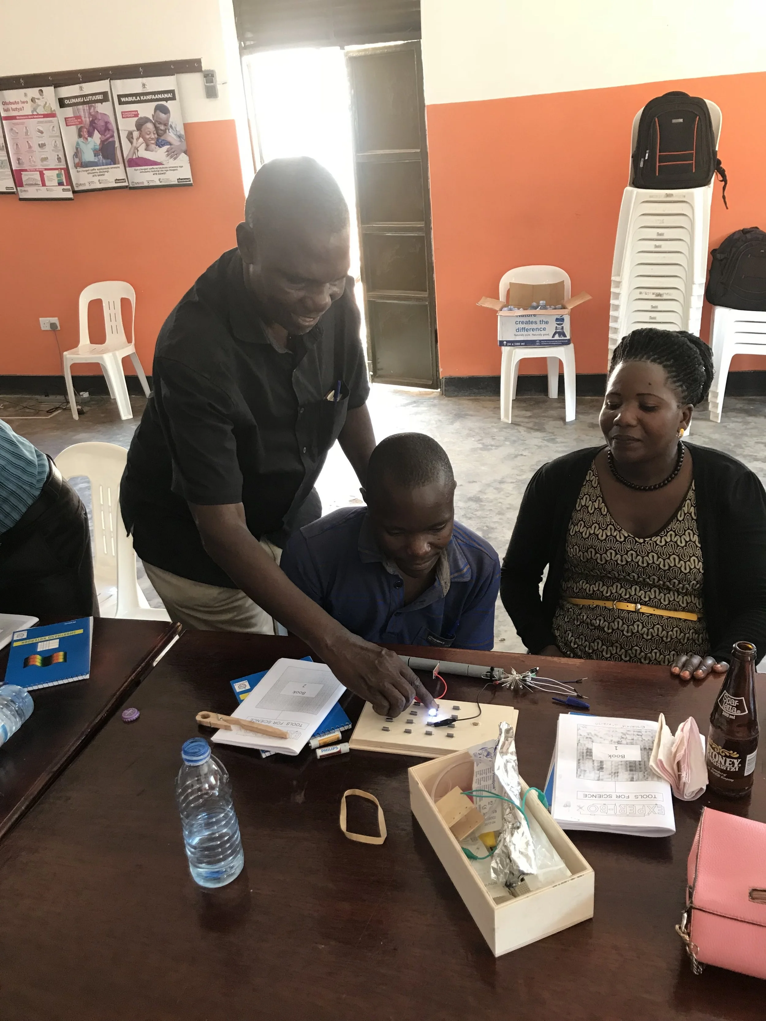 School Program Coordinator Max Ssenyonga Works with teachers using the Experi-Box to show how electric circuits works.