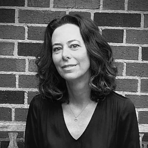 A smiling woman therapist smiling with brick background