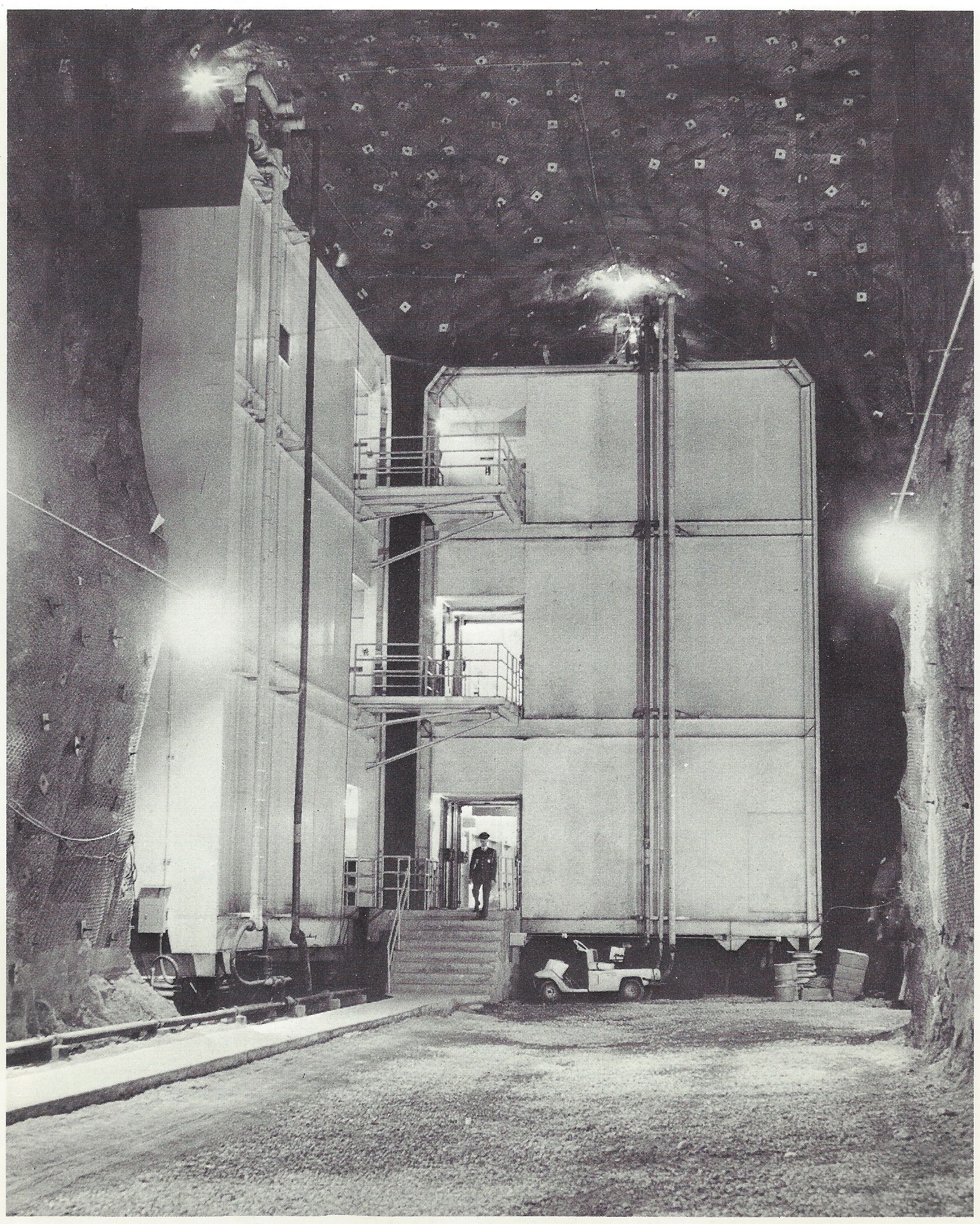  Caption: "These are two of the eleven buildings in the NORAD complex. While it possible to pass from one building to another through vestibules, the structures do not touch one another, nor do they touch the ceilings or walls of their granite cave. 