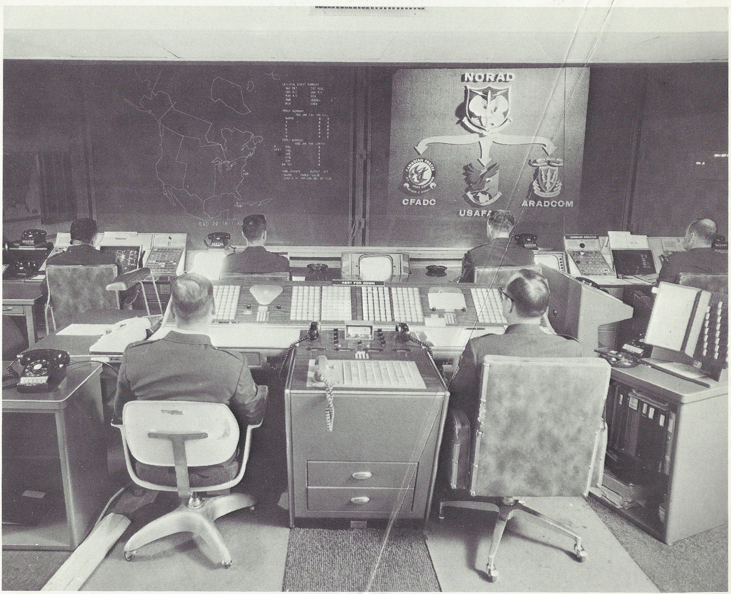  Caption: "AIR DEFENSE WATCH - These display screens would display signs of air attack against Canada and the United States. By pushing buttons, the NORAD battle staff members can take an electronic look at the tracks of space satellites or aircraft,
