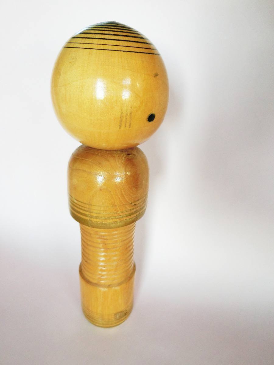Naive style kokeshi doll with golden stripes
