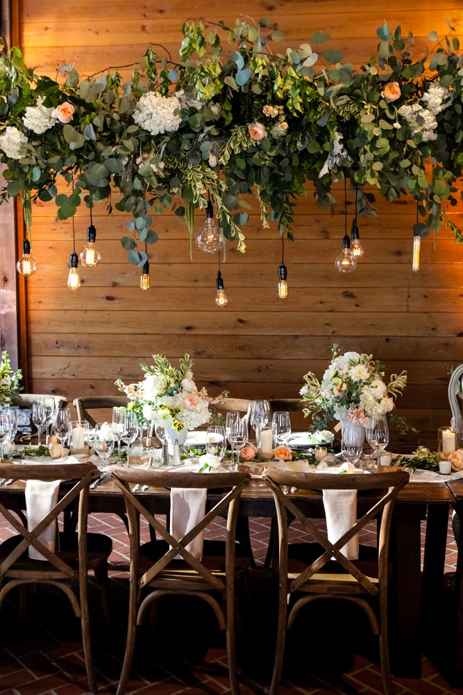 fetenashville.com | Franklin Wedding at Trinity View Farm | Shawn Johnson Gets Married to Andrew East | Fete Nashville Wedding Planning and Design | best wedding planner | nashville best wedding planner | Luxury Weddings | Celebrity Wedding Planner | greenery hanging over head table | lace runner | exposed bulbs | celebrity bride | celebrity groom | farm wedding | farm tables