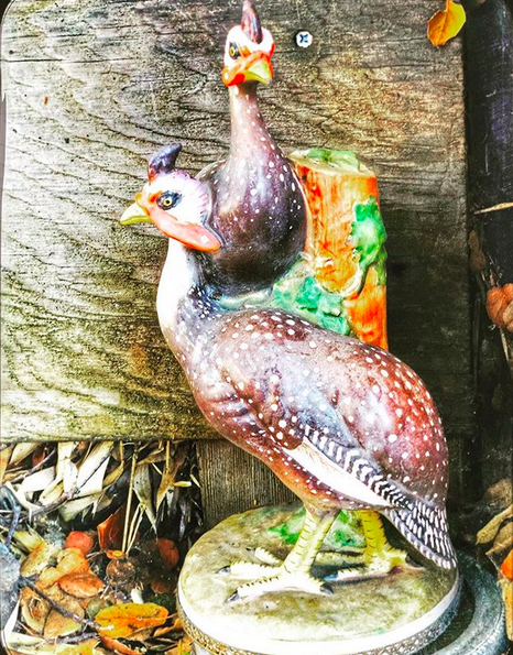 A photo of a vintage (or vintage looking) garden display statue of two guineafowl.