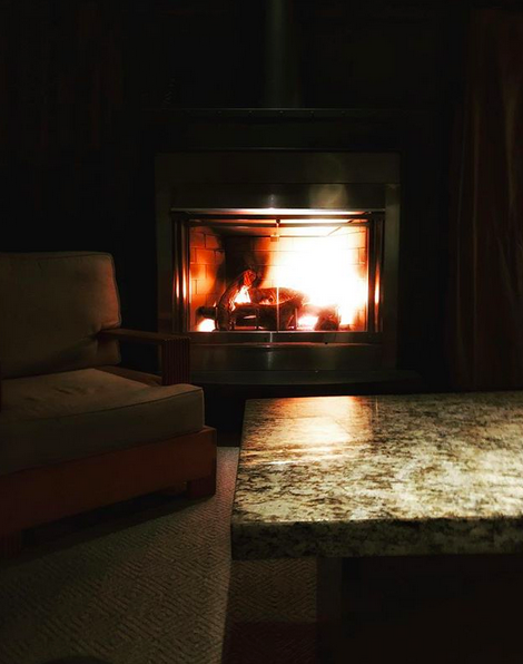 A night photo of a dark living room with a roaring fire in the fireplace.