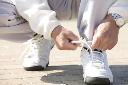47076551_S_man_senior_exercise_sneakers_watch_tie_laces_bend.jpg
