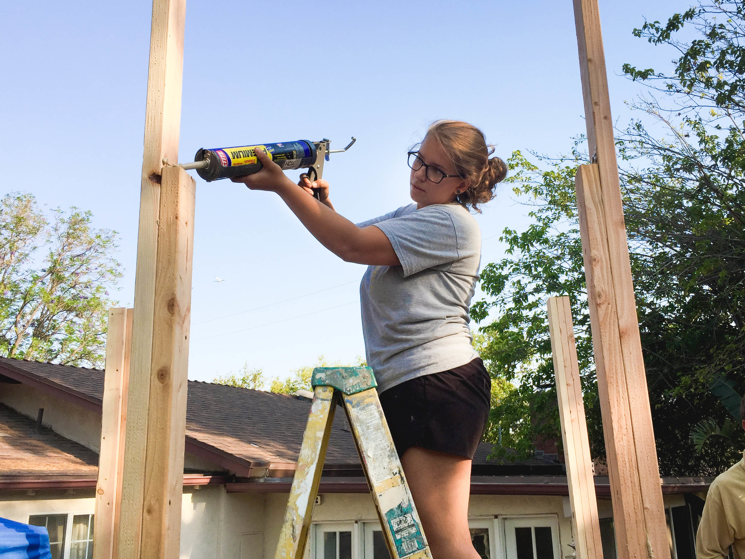 Jen gluing the top of the jack stud where the 4x4 header for the door will go.