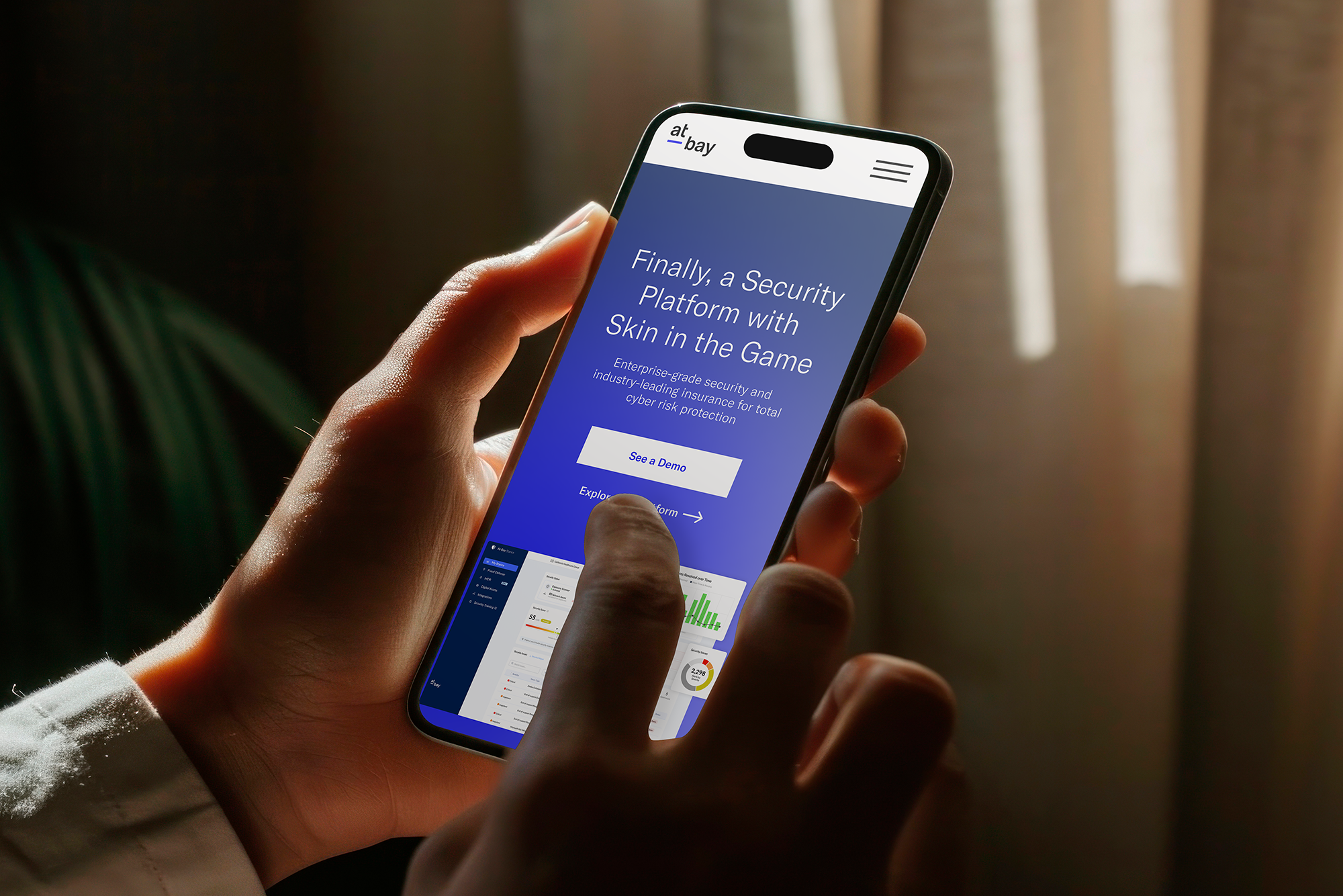 A person holding a smartphone displaying a website for a security platform called alt_bay, with a blue background and white text promoting enterprise-grade security and cyber risk protection.