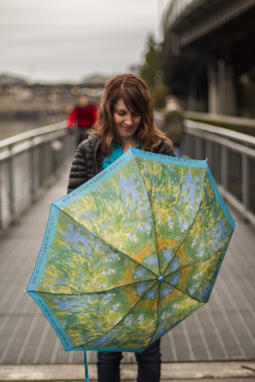 Alyssa on the bridge with a bright blue, green, yellow and orange open umbrella