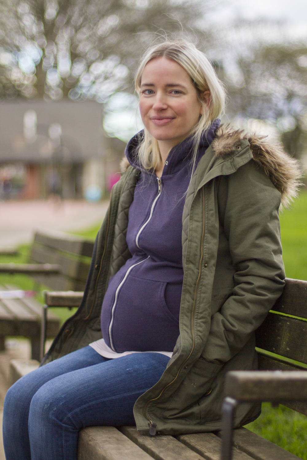 Megan sitting on a park bench with a pregnant belly