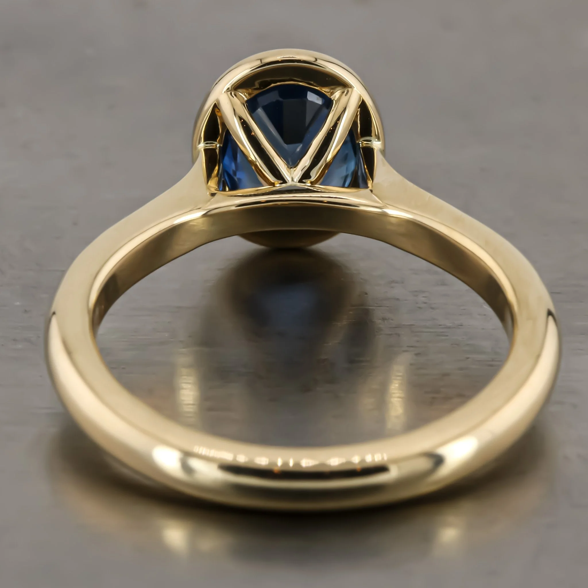 Gold ring with a blue gemstone, shot from the side showing the setting and band.