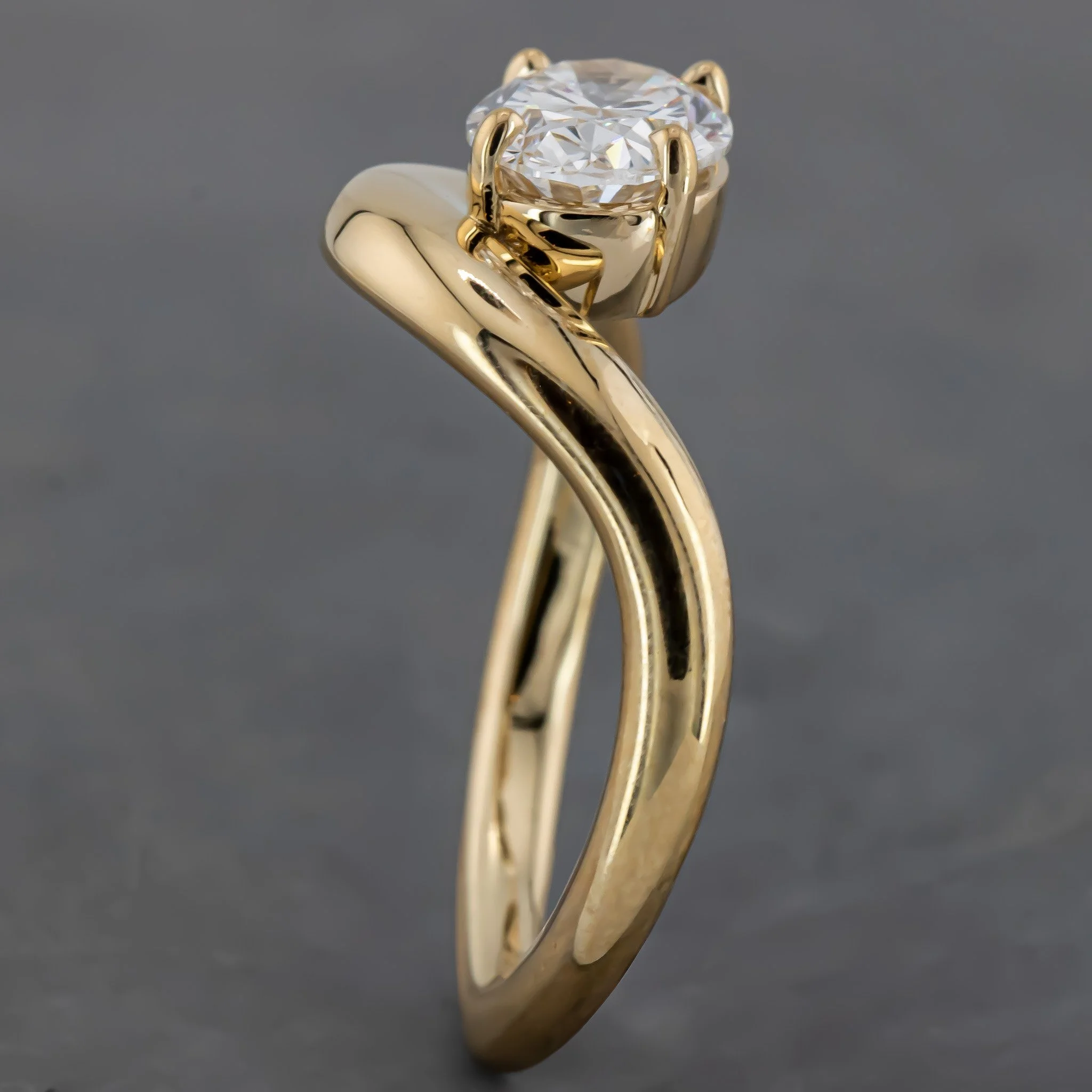 Close-up of a gold engagement ring with a large, round-cut diamond in a six-prong setting.