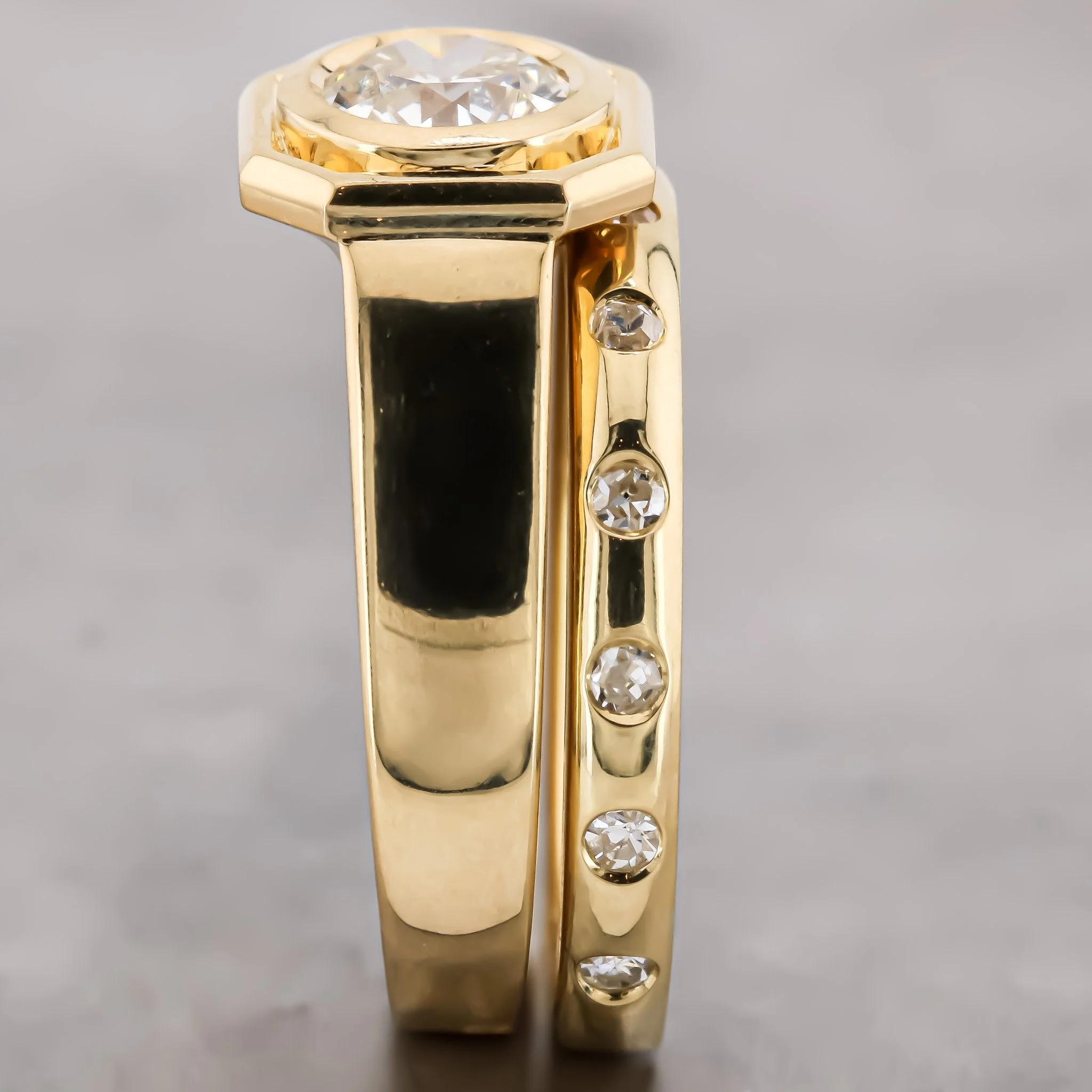 A gold ring with a large clear gemstone on top, set in a bezel setting, and smaller gemstones embedded along the band.