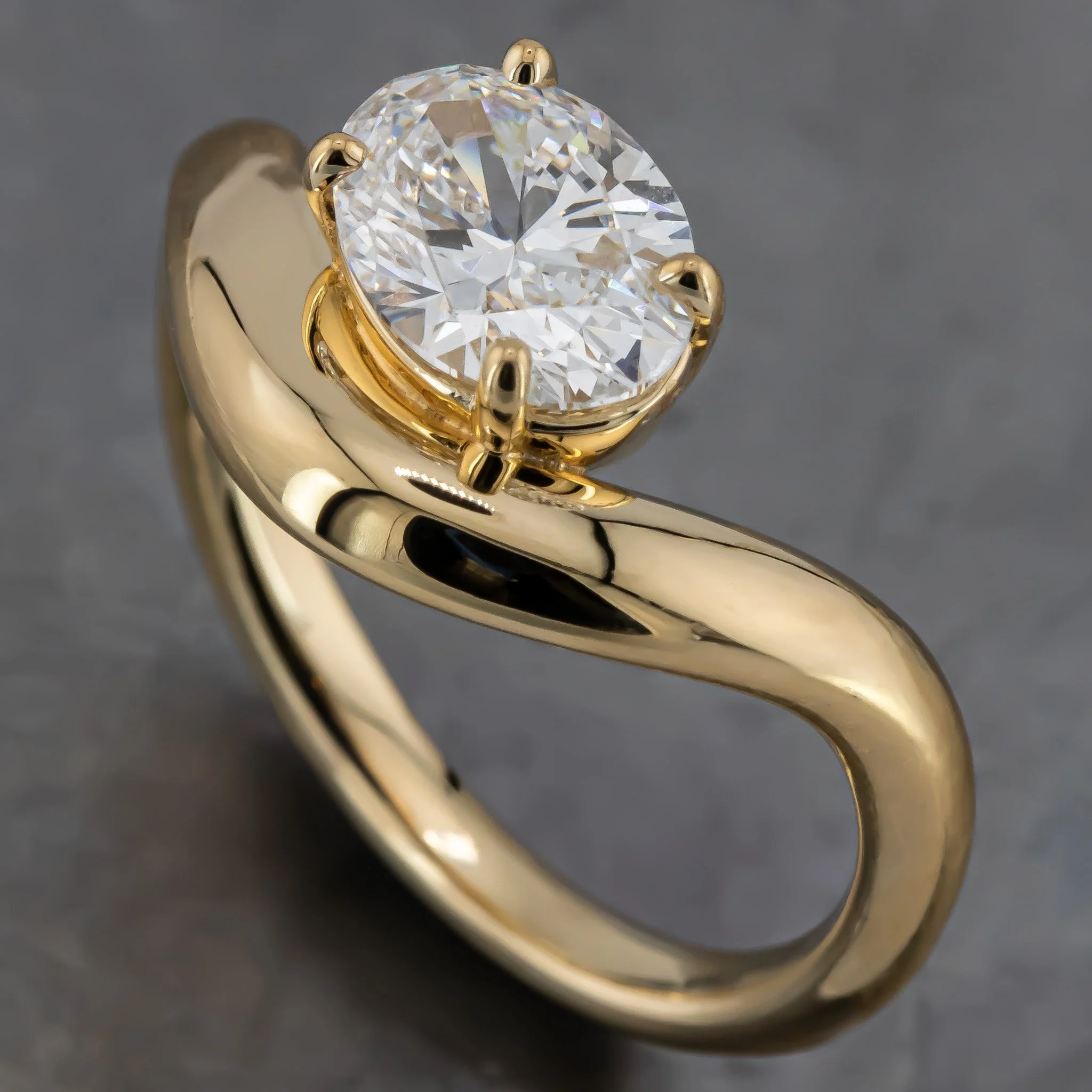 Close-up of a gold engagement ring with a large round diamond held by four prongs.