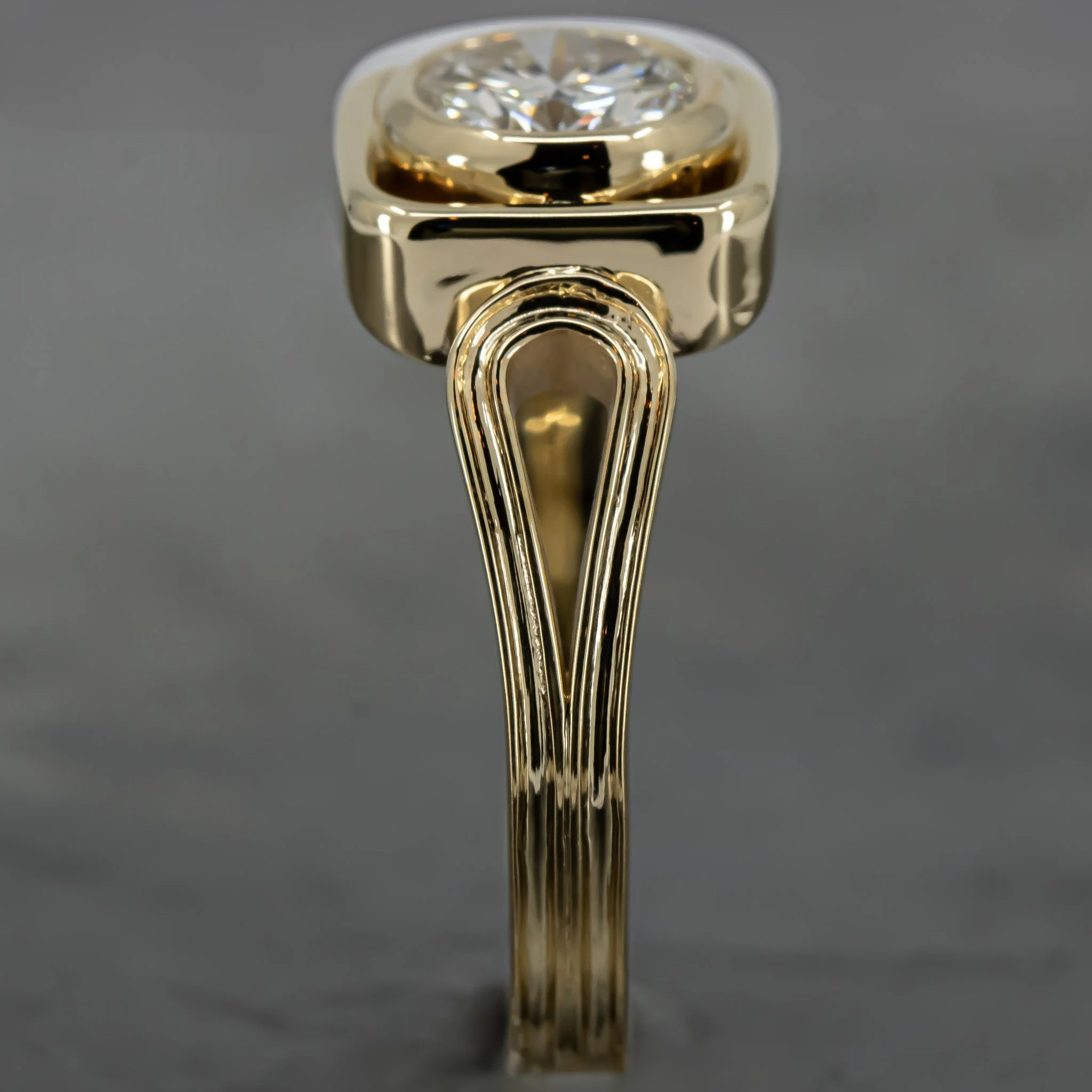 Close-up of a gold ring with a large diamond on a gray background.