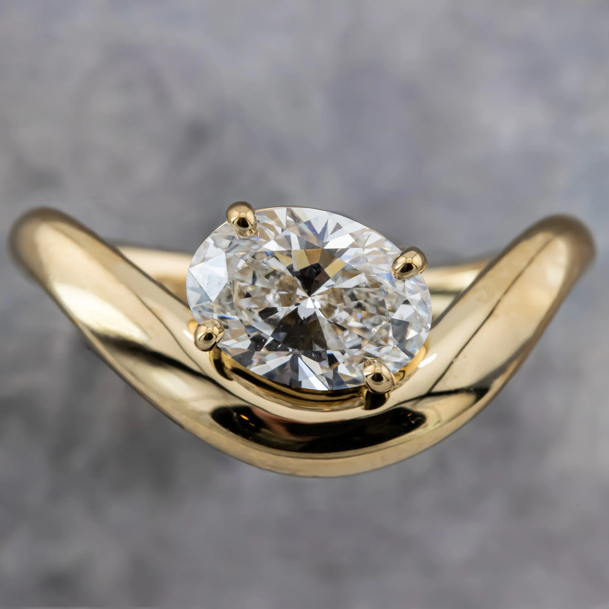 Close-up of a gold ring with a large, round diamond mounted in a four-prong setting.