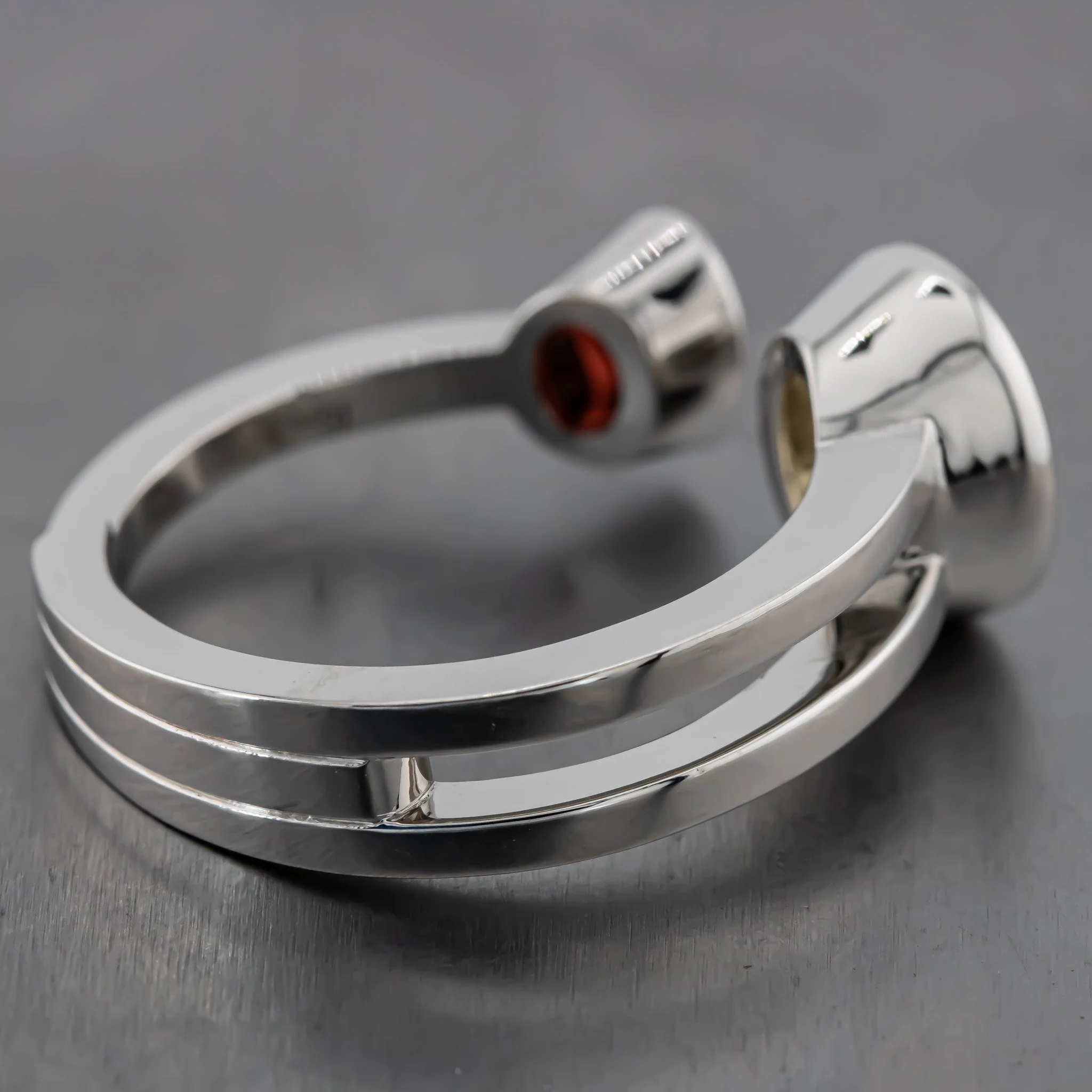 Close-up of a metal watch clasp with a red accent, resting on a dark surface.