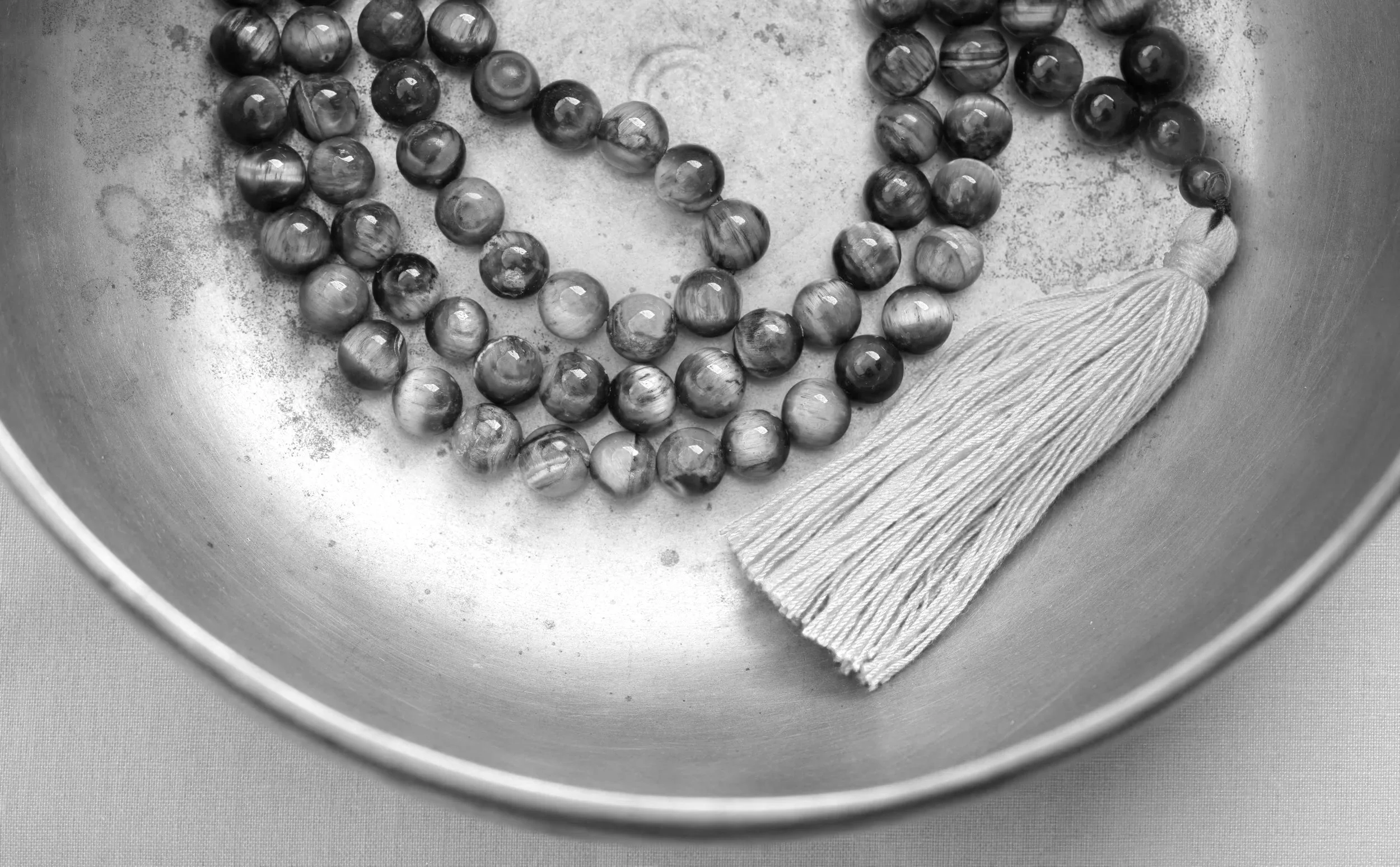 Black marbles inside a metallic bowl with a cloth at the edge of the bowl.