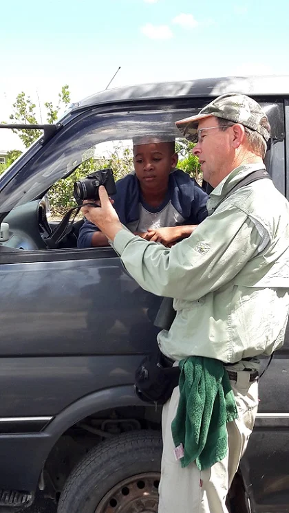 Shane on Barbuda showing a young local boy a photo of the warbler endemic to his island.