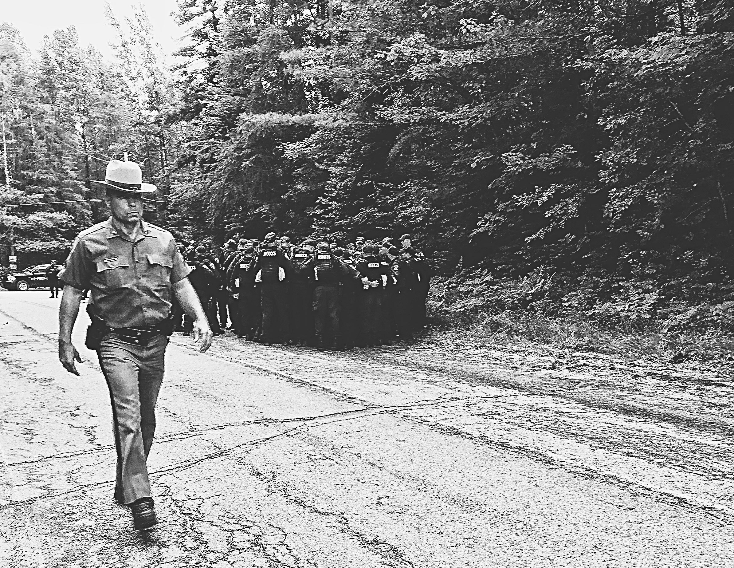  A New York State trooper walks by a group of corrections officers in Owls Head N.Y. The search for Richard Matt and David Sweat has moved to this area after DNA evidence is recovered from a nearby cabin. &nbsp;(Chelsia Rose Marcius/June 23, 2015)&nb